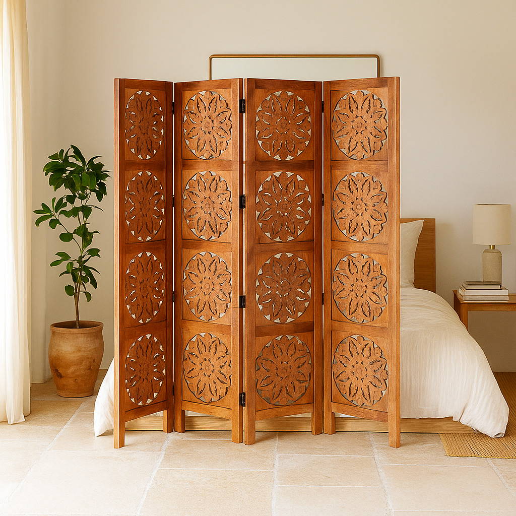 Lifestyle image of a foldable room partition made of mango wood, featuring four panels with symmetrical hand-carved circular floral medallions, finished in a rich natural wood tone and connected by black metal hinges for easy folding and adjustment.