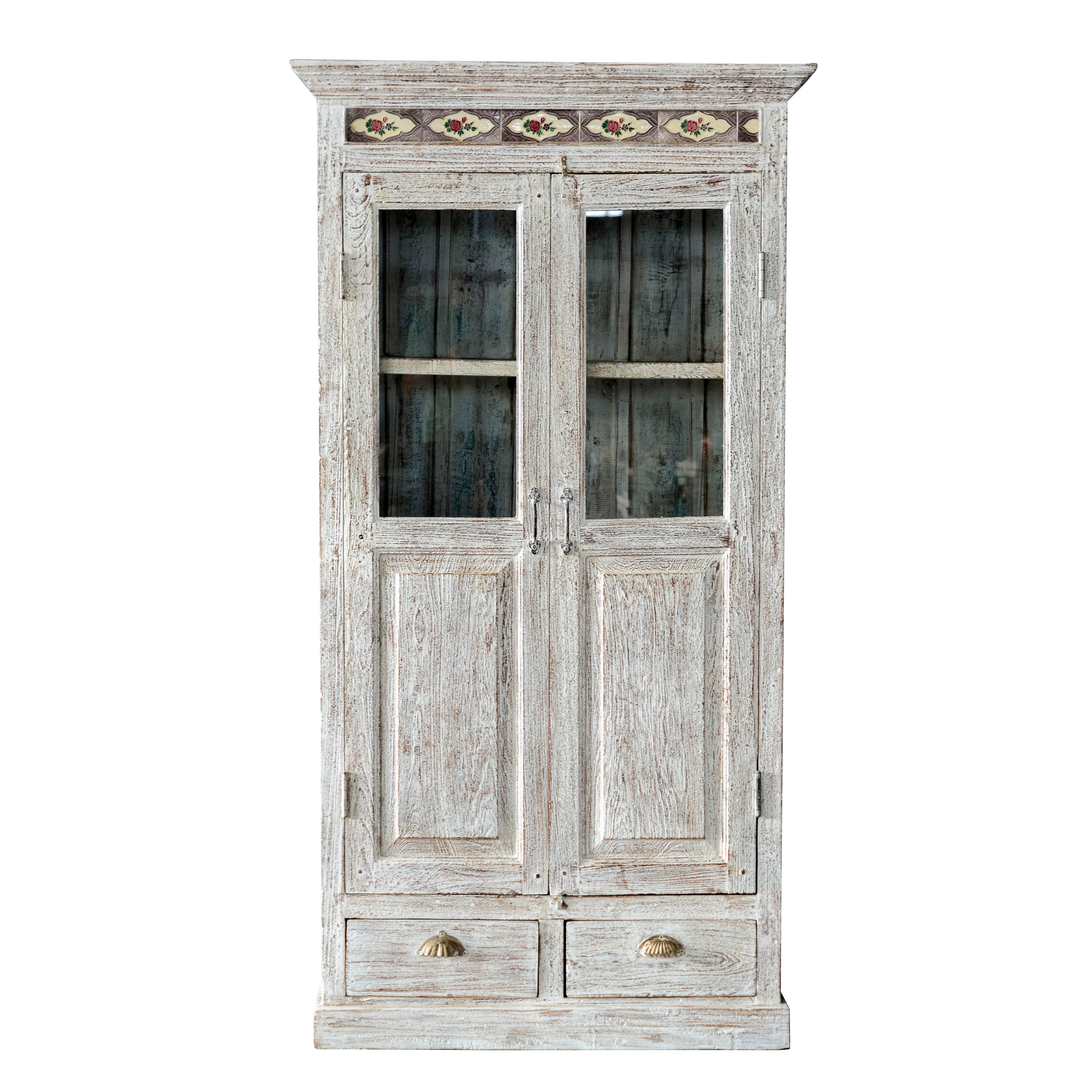 White background image of a reclaimed teak wood cabinet in shabby chic white with glass doors and ceramic inlays – dining room furniture with vintage elegance.