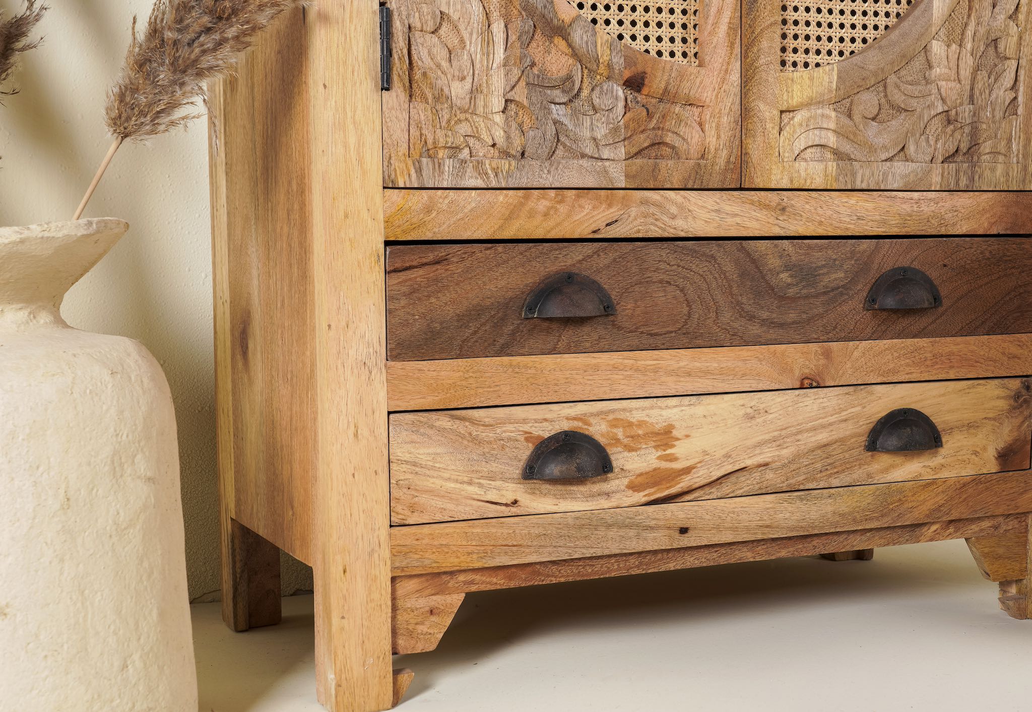 Close up image of a handcrafted mango wood cabinet Agnayi with rattan inserts and floral carvings, rattan furniture for bohemian interior, 80 × 40 × 148 cm.