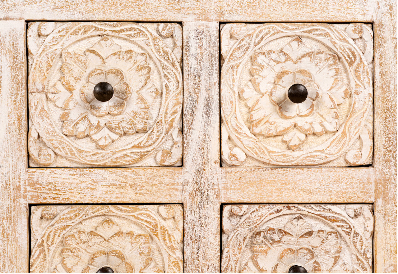 Close up image of a whitewashed mango wood lowboard with hand-carved floral details, eight drawers and two compartments; ideal as a wooden lowboard or carved wood console table, 180 × 60 × 40 cm.