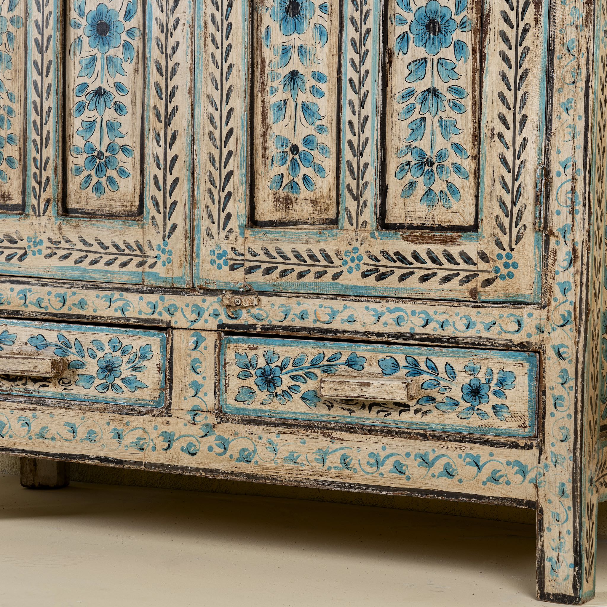 Close up image of the leg part of a hand painted wooden furniture cabinet with floral motifs, reclaimed teak artisanal furniture in Mediterranean style, 95 × 40 × 152 cm.