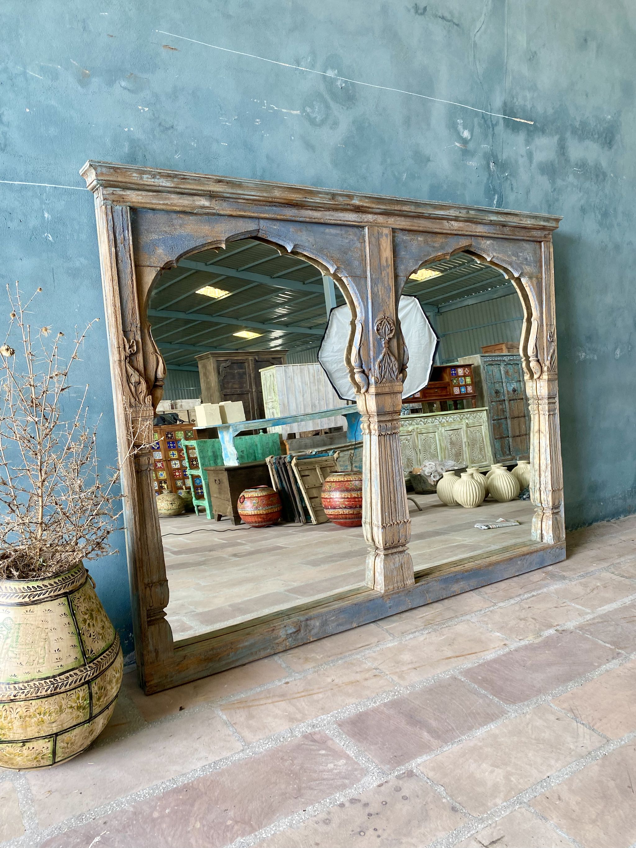Life style image of a Indian triple-arched teak wall mirror with indigo patina, perfect for vintage home decor or a boho chic living room.