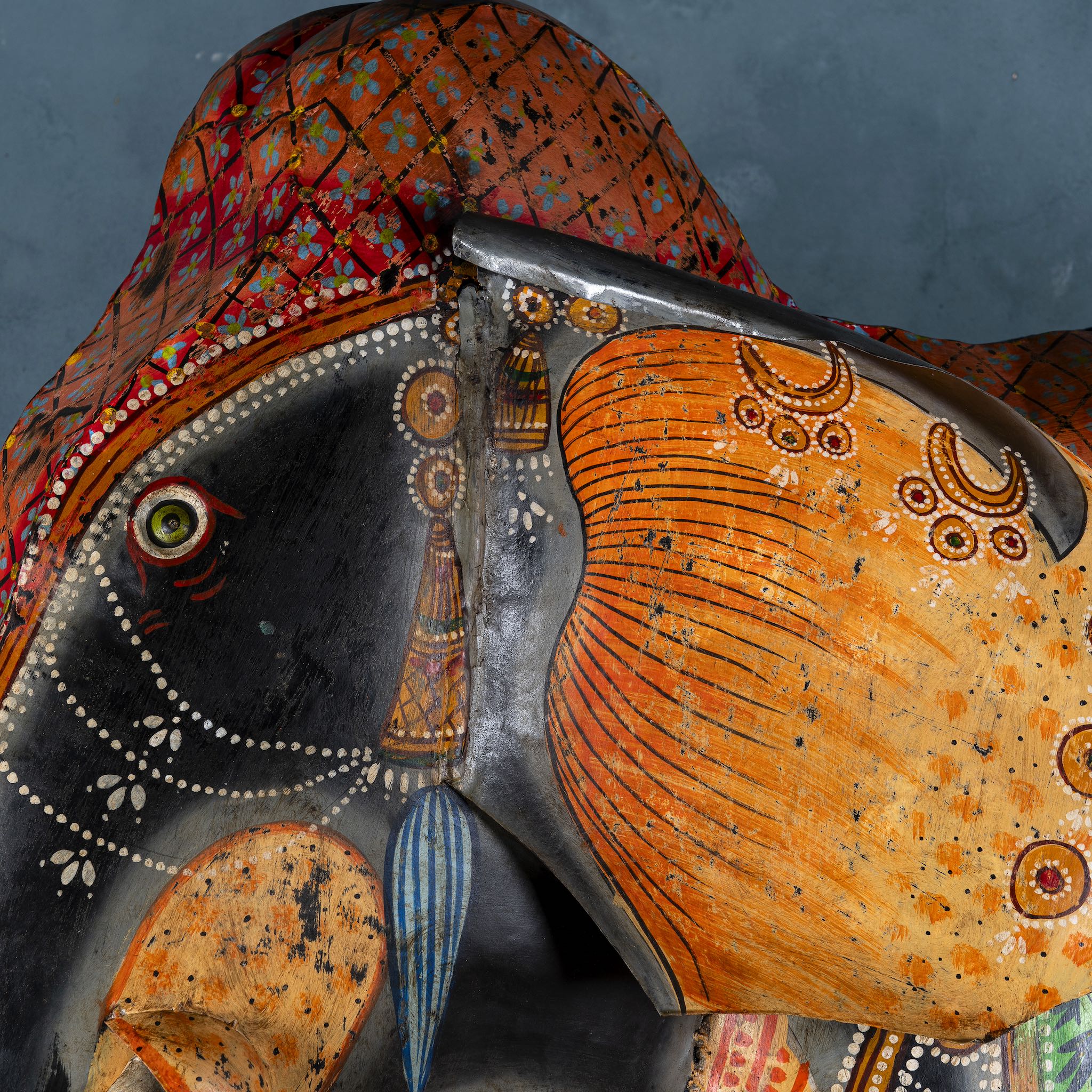 Close up of a large hand-painted decorative elephant sculpture made of sheet metal in vibrant Rajasthani style, featuring intricate floral and geometric patterns in red, green, and gold. Ideal for enhancing entrance areas, restaurant lobbies, hotel receptions, or luxury interior spaces.
