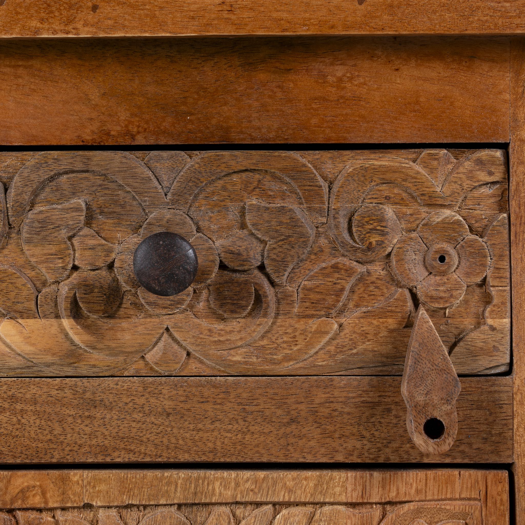 Close up image of a pair of mango wood night stands with floral hand carvings in natural wood colour.