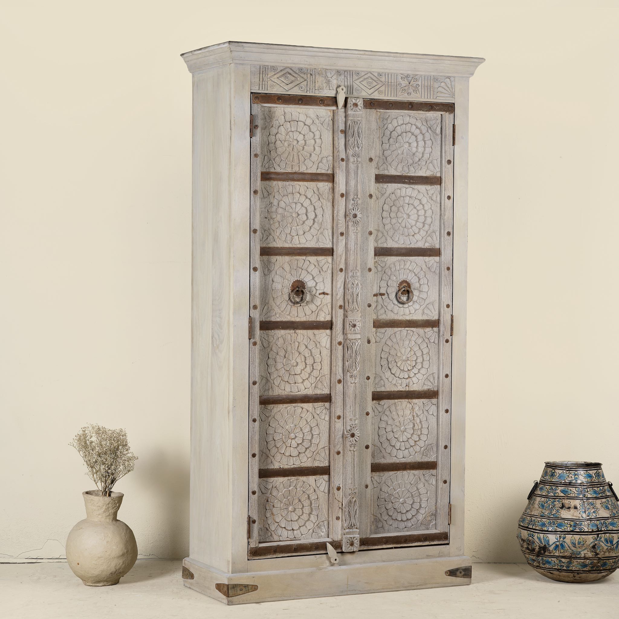 Side angle image of a old door cabinet with reclaimed teak doors, floral carvings, and iron accents; artisan teak wood wardrobe with mango wood frame, 100 × 44 × 206 cm.