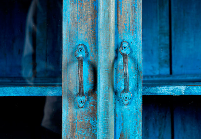Close up image of a refurbished blue teak wood showcase with glass and wooden doors – sustainable dining room furniture crafted from reclaimed teak with vintage flair.