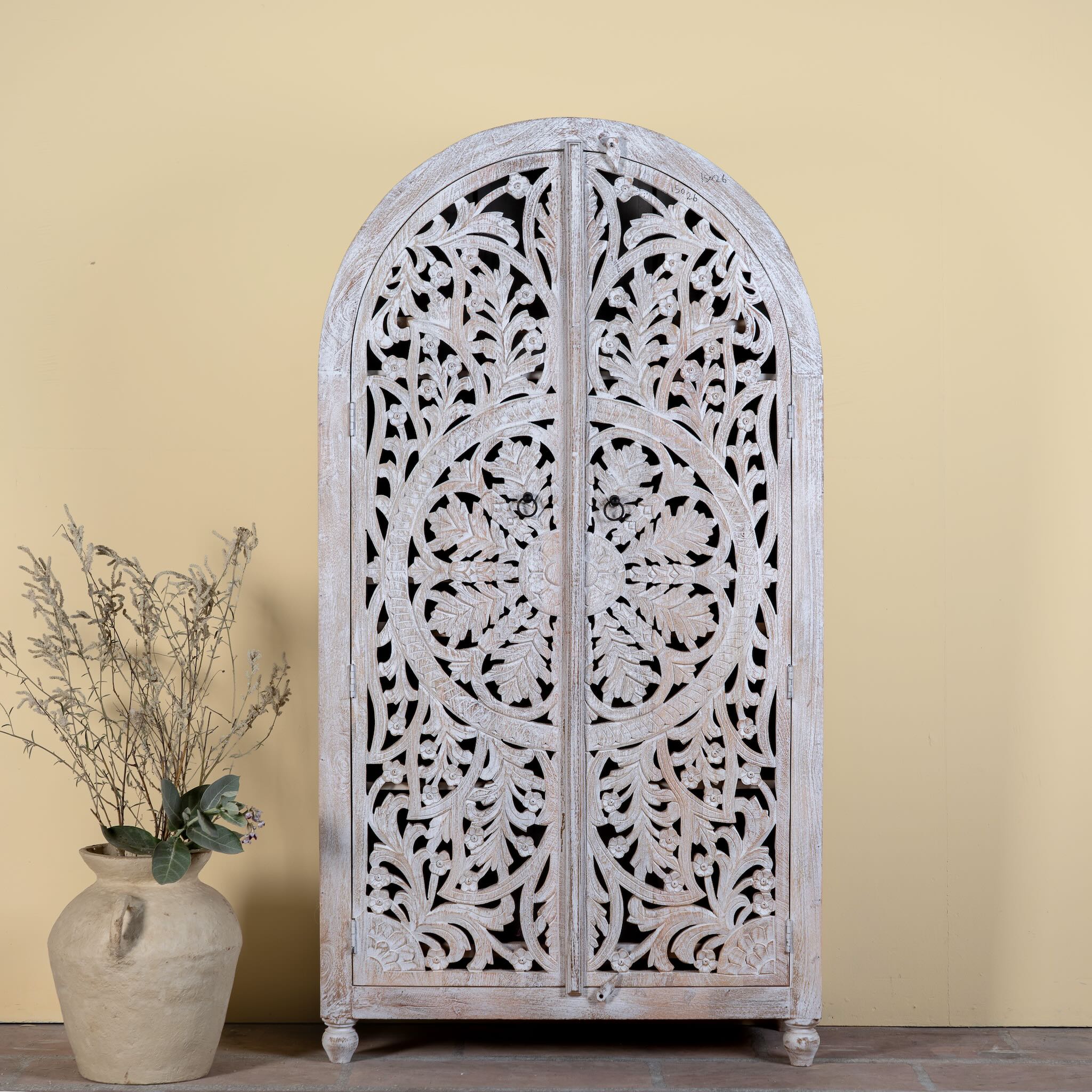 Bhuvana arched mango wood wardrobe featuring a sculptural half-round design, intricate hand-carved floral detailing, and carved legs—an artisanal piece in the collection of arched wardrobes and mango wood wardrobes.