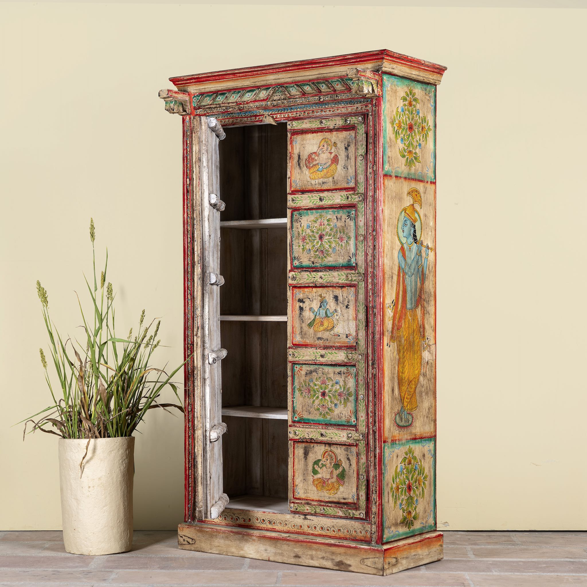 Side angle with open door image of a antique hand painted wardrobe made from reclaimed teak wood with Indian motifs; unique furniture and teak wood furniture, 113 × 50 × 190 cm.