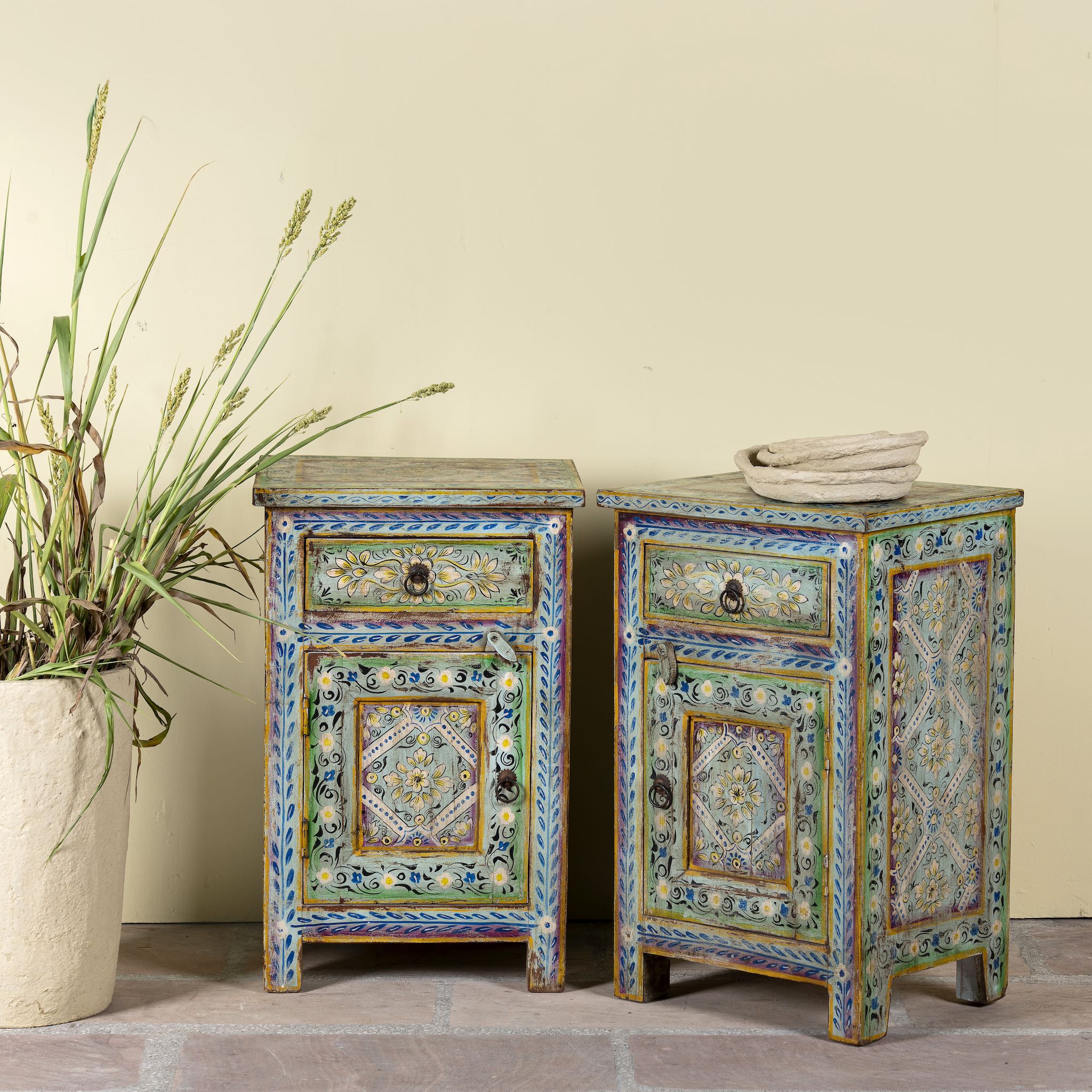 Side angle image of a pair of hand-painted nightstands made of reclaimed wood in boho style, sustainable furniture with drawer and cabinet, 45 × 35 × 70 cm.