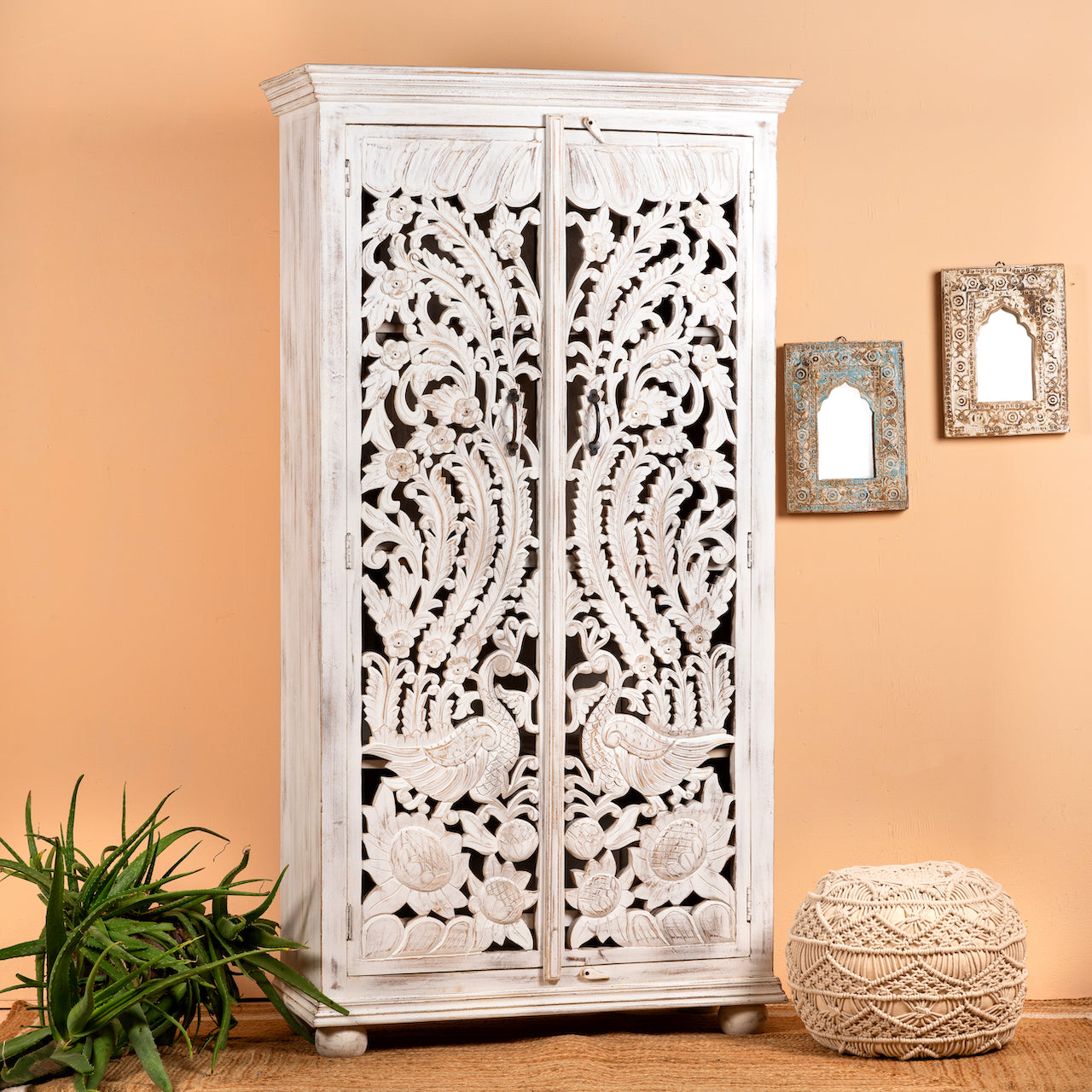 Lifestyle image of a hand-carved mango wood wardrobe with peacock and floral motifs, whitewashed finish; elegant wooden wardrobe and mango wood furniture, 190 × 100 × 40 cm.