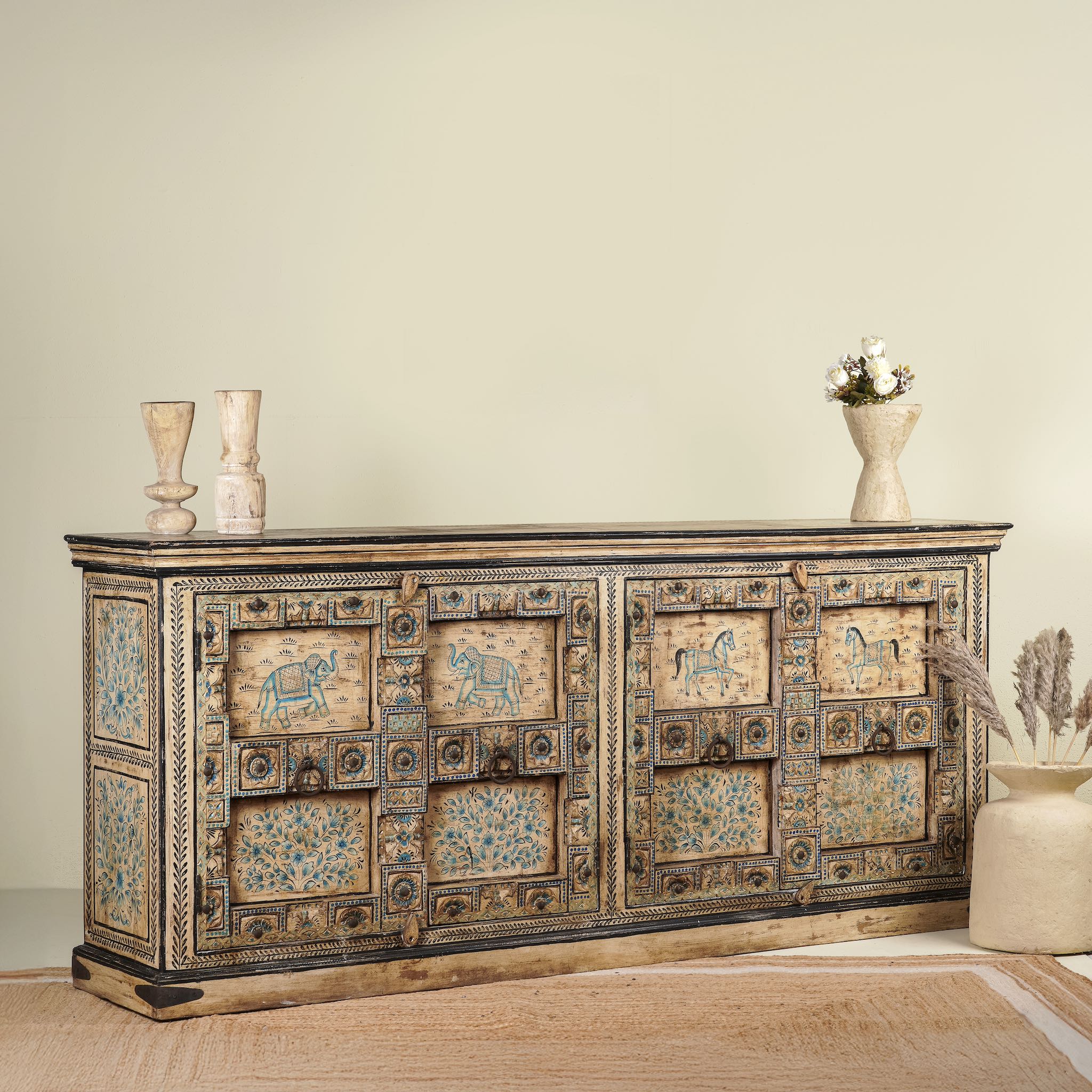 Side angle image of a unique sideboard made of recycled wood with hand painted Indian motifs in blue and gold; sustainable furniture for dining rooms or hallways, 220 × 44 × 98 cm.