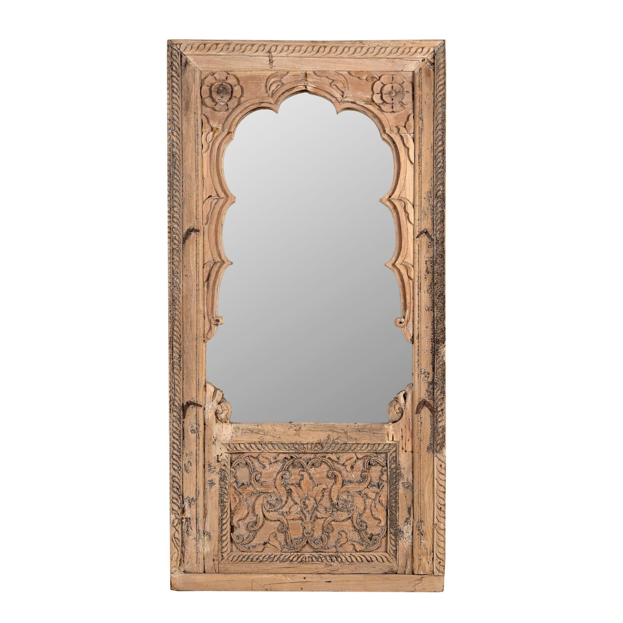 White background image of a hand-carved mirror crafted from an old teak wood window frame, featuring intricate floral and scrollwork details with a natural distressed finish and an arched top design reflecting traditional Indian craftsmanship.