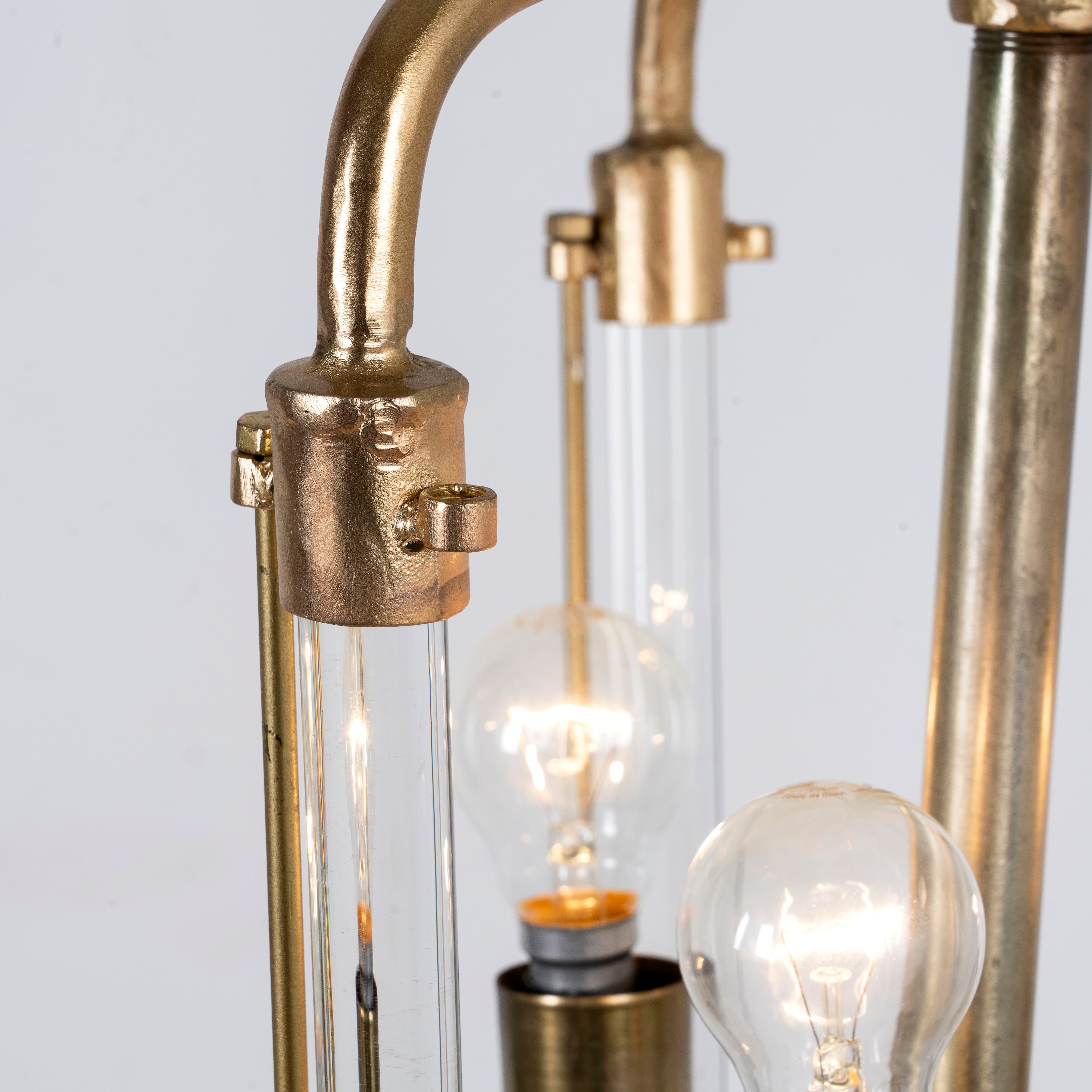 Close up image of a large round pendant lamp in antique brass with test tube glass – minimalistic style pendant light combining vintage metal lighting and elegant glass accents.