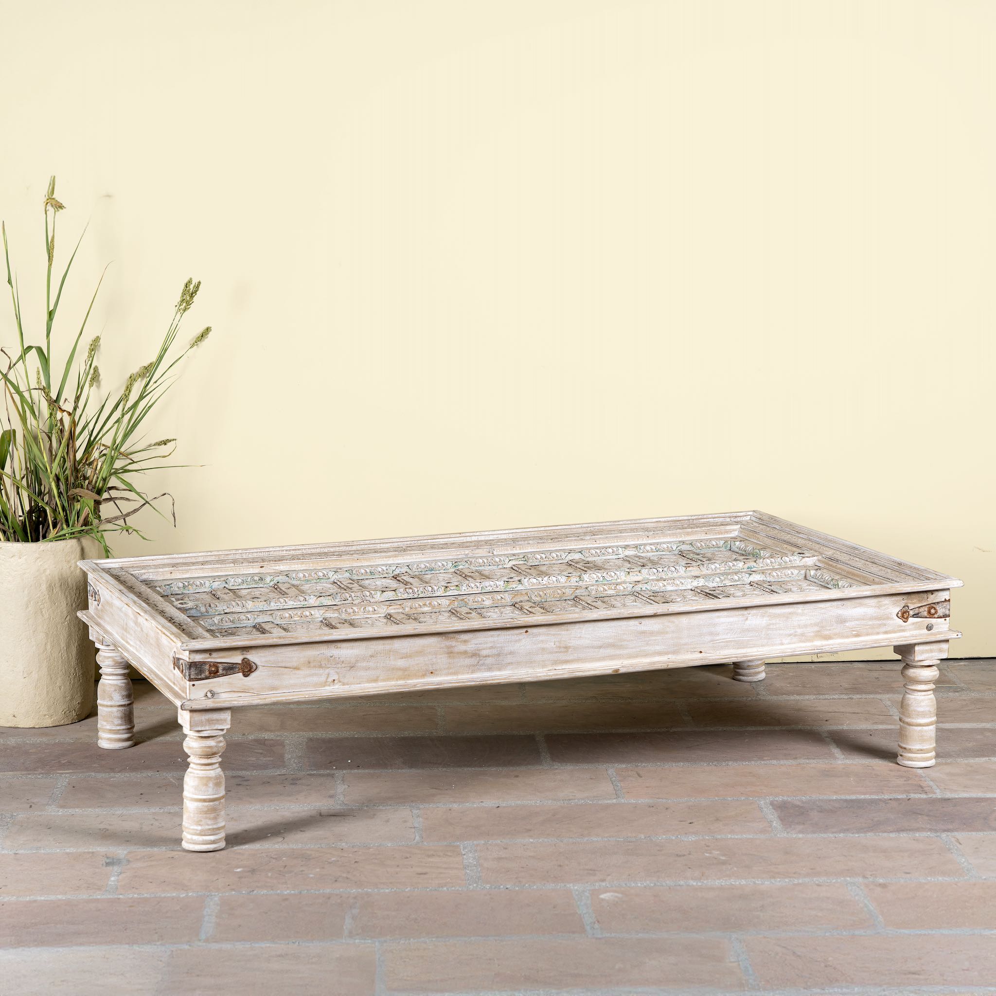 Side angle image of a white washed old door coffee table made of antique teak wood; handcrafted Indian coffee table, 183 × 100 × 45 cm.