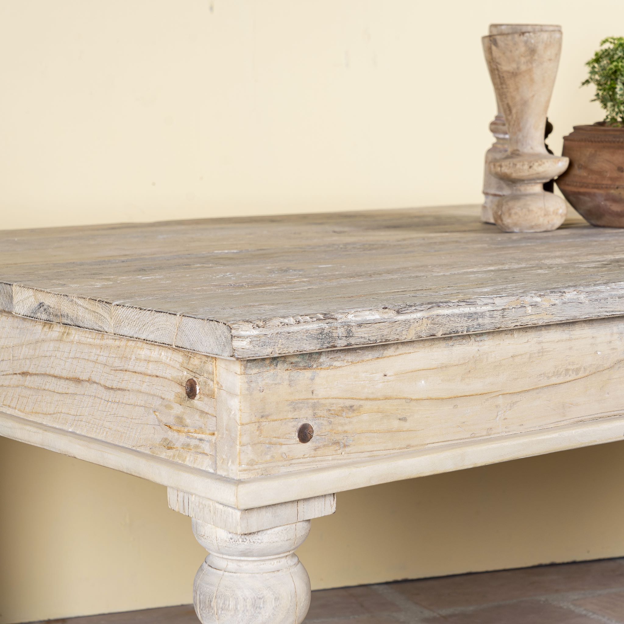 Close up image of a sandblasted reclaimed wood dining table with carved legs, sustainable dining room furniture, 220×100×75 cm.