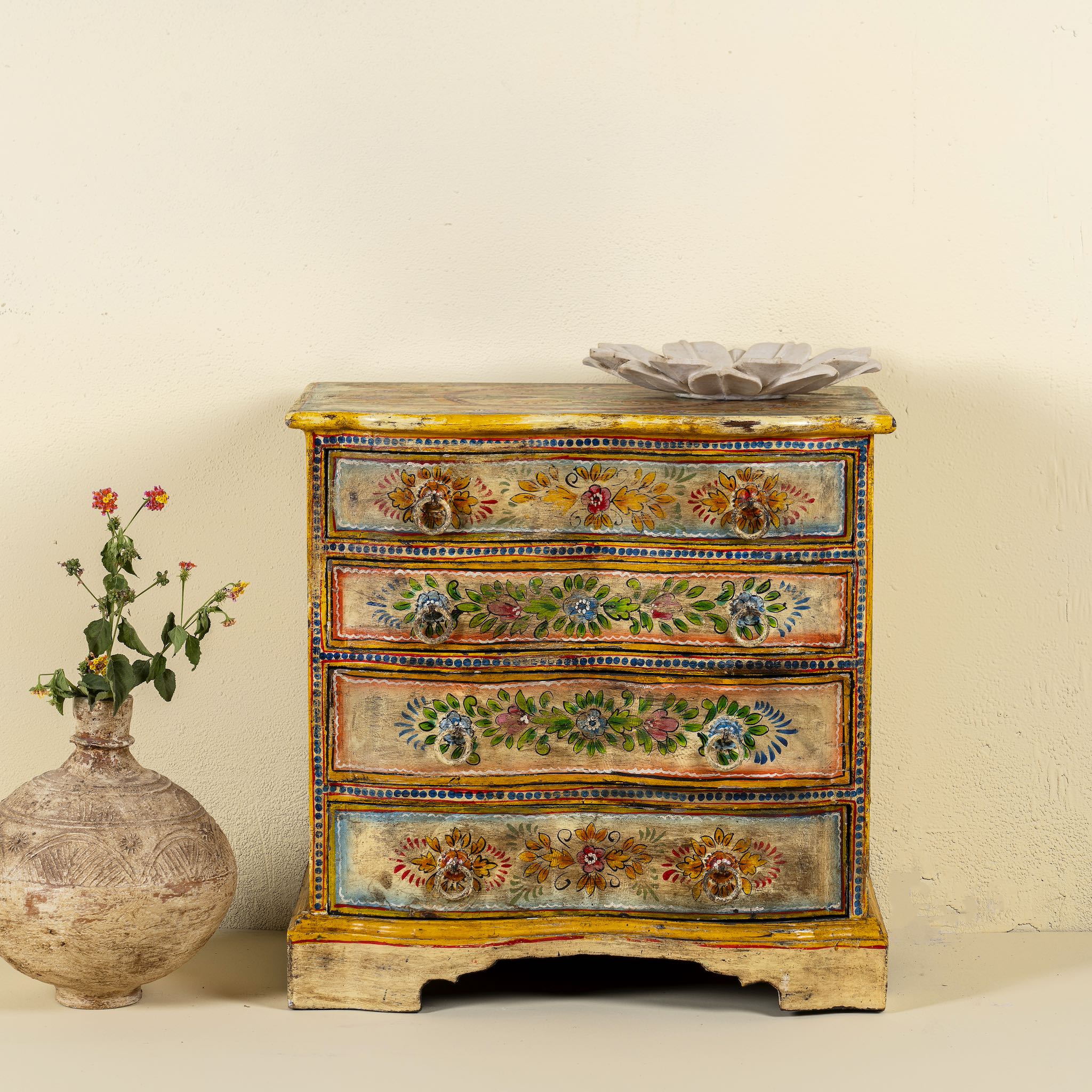 Hand-painted reclaimed wood chest of drawers with floral designs and distressed antique finish; perfect for bohemian interiors and vintage hand painted furniture lovers.