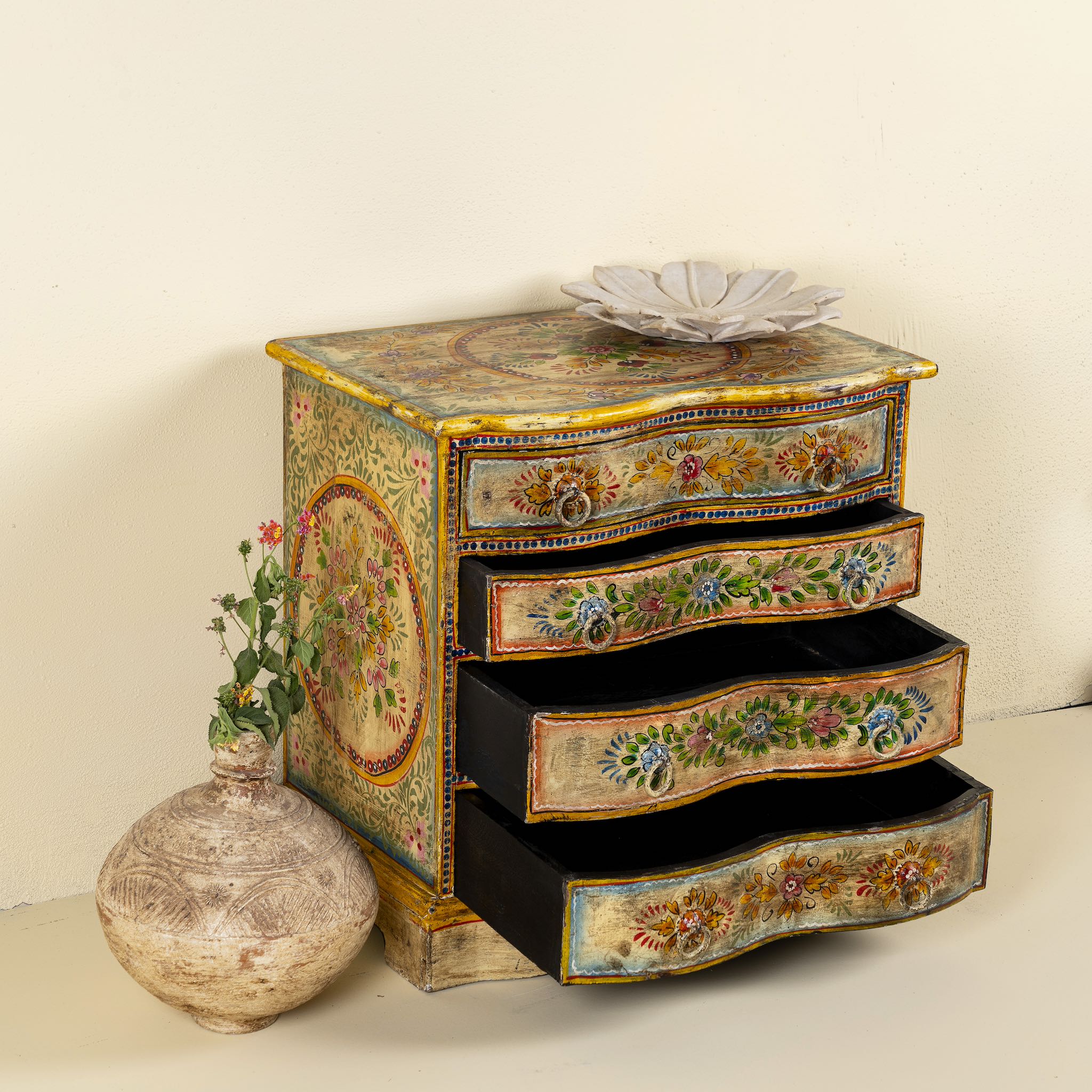 Side angle with open drawers image of a hand-painted reclaimed wood chest of drawers with floral designs and distressed antique finish; perfect for bohemian interiors and vintage hand painted furniture lovers.