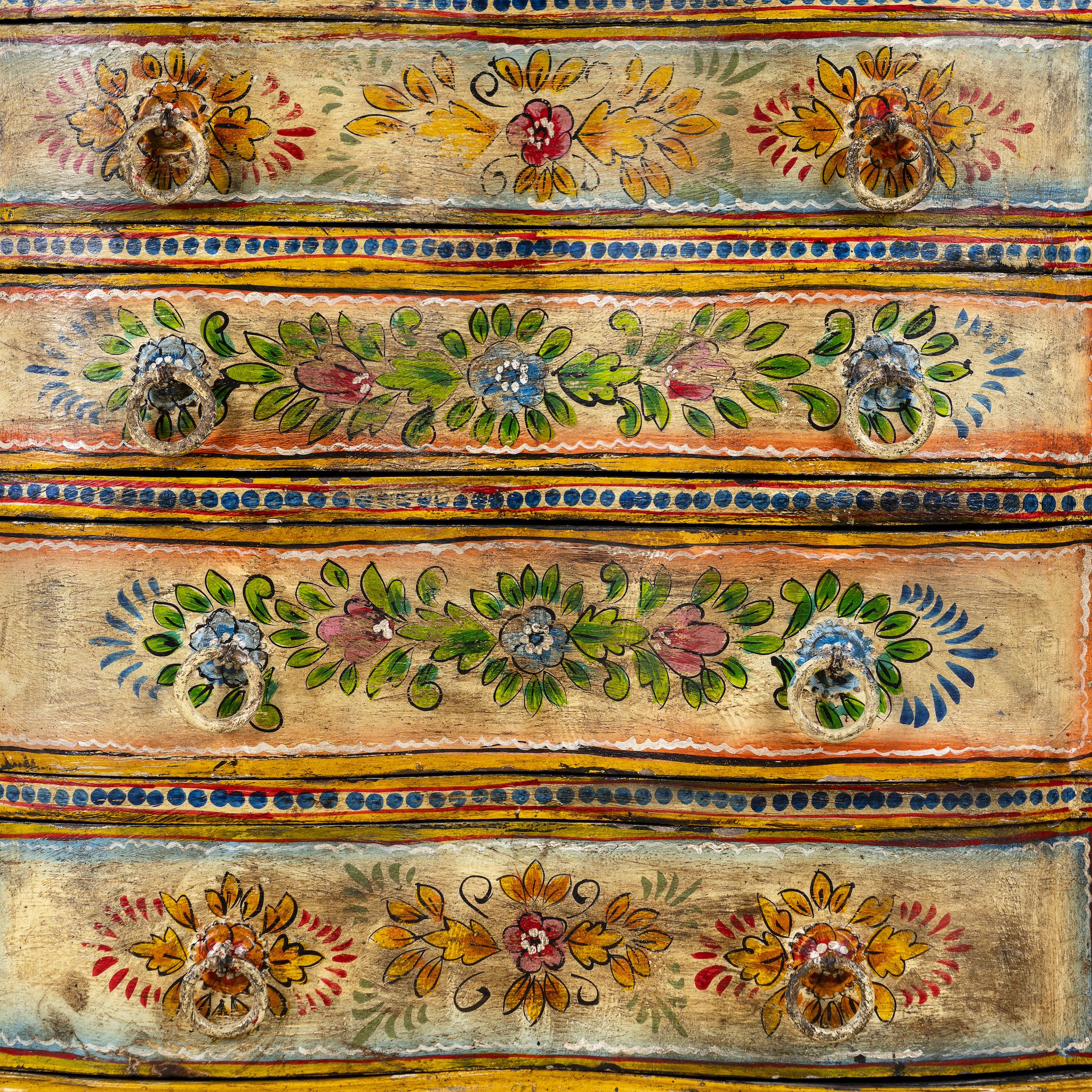 Close up image of a hand-painted reclaimed wood chest of drawers with floral designs and distressed antique finish; perfect for bohemian interiors and vintage hand painted furniture lovers.