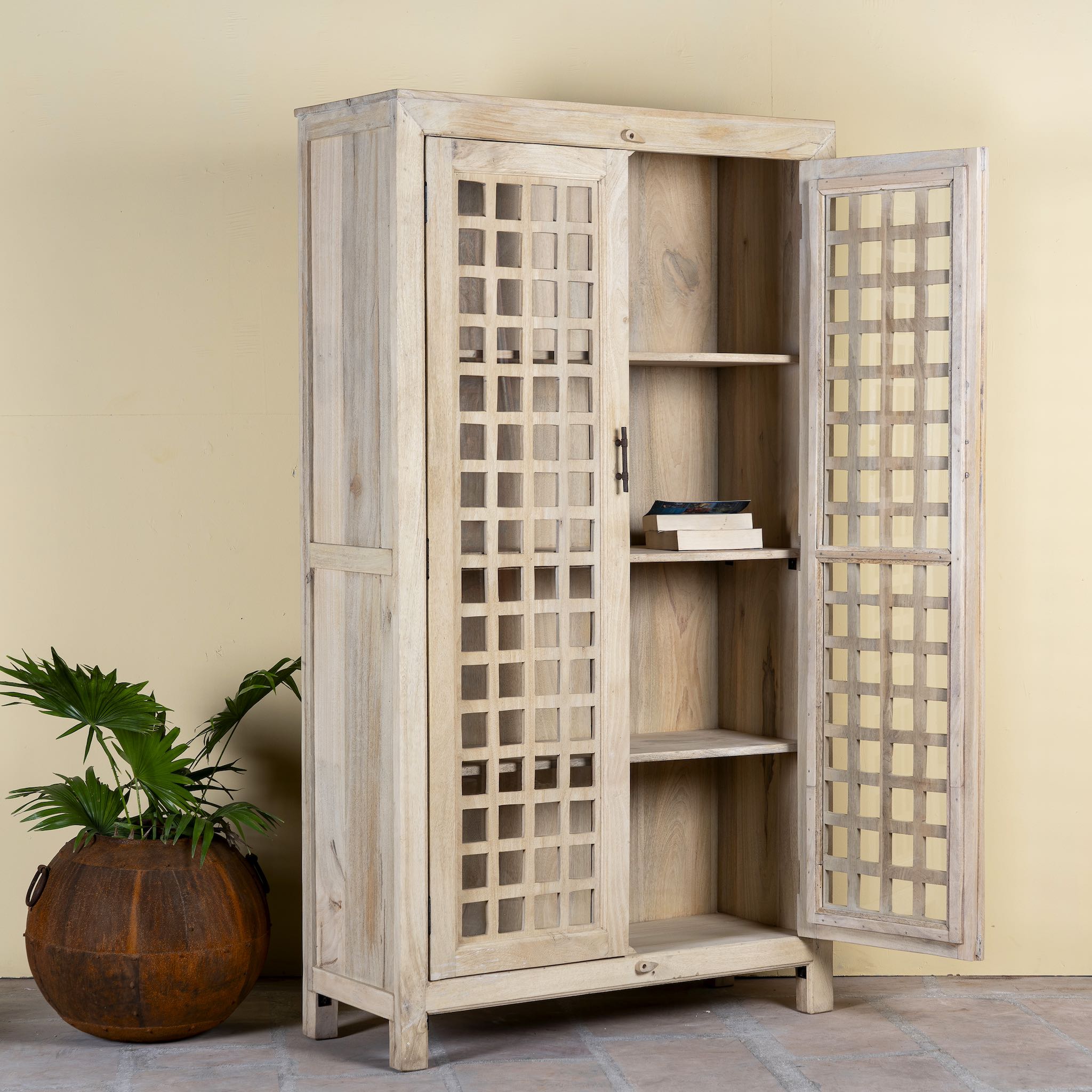 Open door image of a sandblasted mango wood showcase with two glass-panelled grid doors and four interior compartments, finished in a light sun-washed tone, ideal as living room furniture.