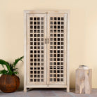 Sandblasted mango wood showcase with two glass-panelled grid doors and four interior compartments, finished in a light sun-washed tone, ideal as living room furniture.