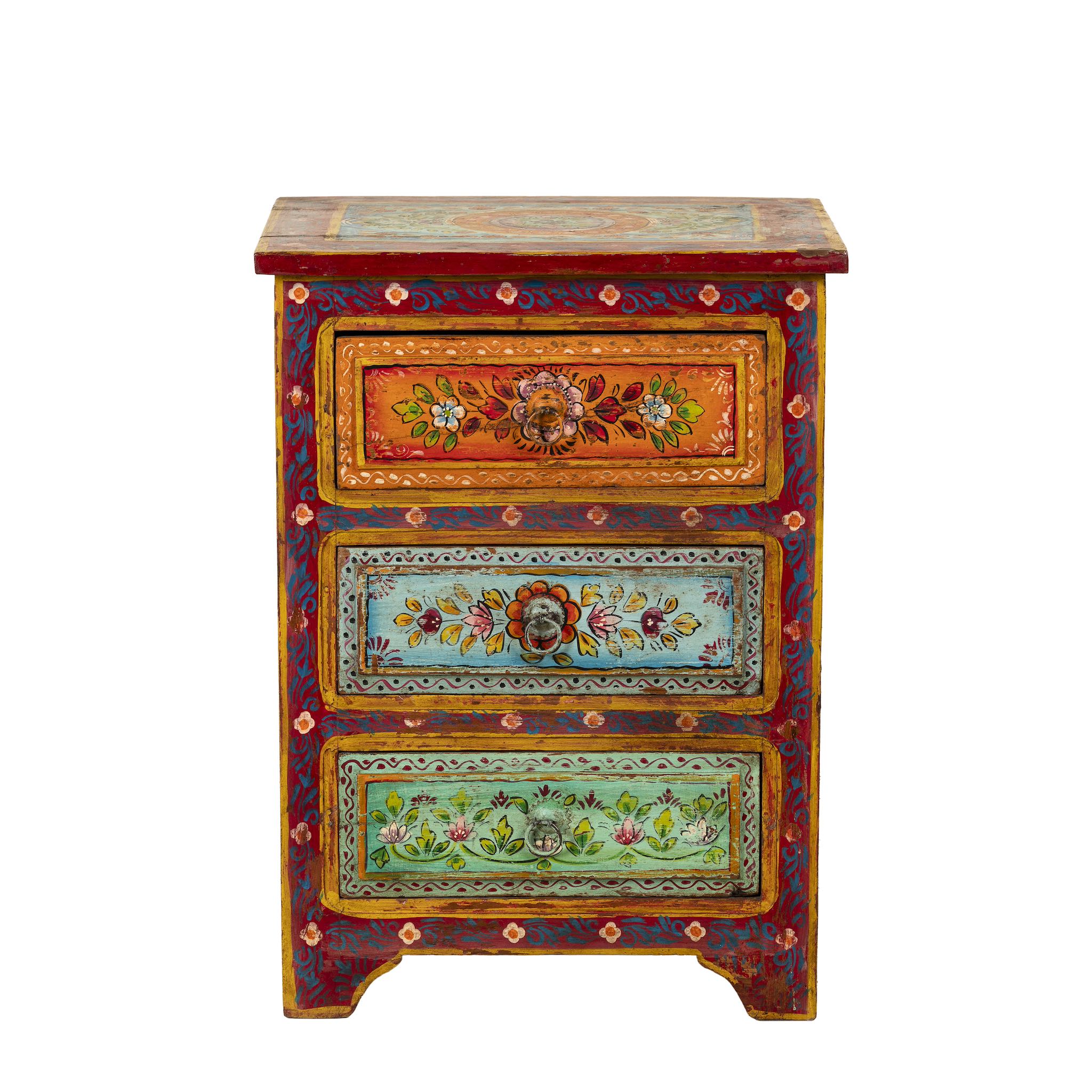 White background image of a hand-painted reclaimed wood nightstand with multiple drawers, featuring vibrant colours and floral patterns, placed next to a vase with dried plants.