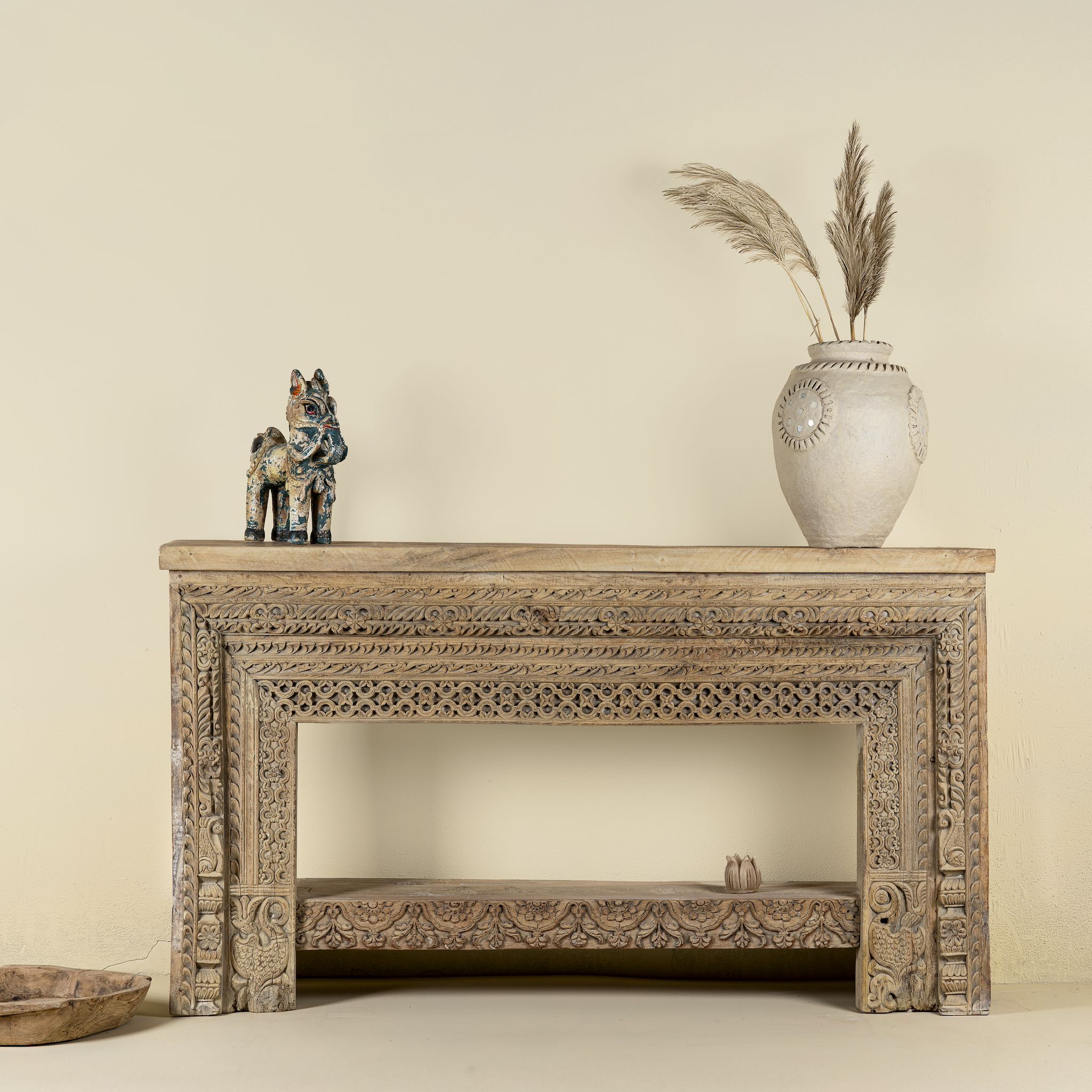 Front view image of a ornate console table crafted from reclaimed teak wood and refurbished architectural elements, featuring intricate hand-carved detailing with floral and geometric motifs, showcasing a vintage artisanal aesthetic.