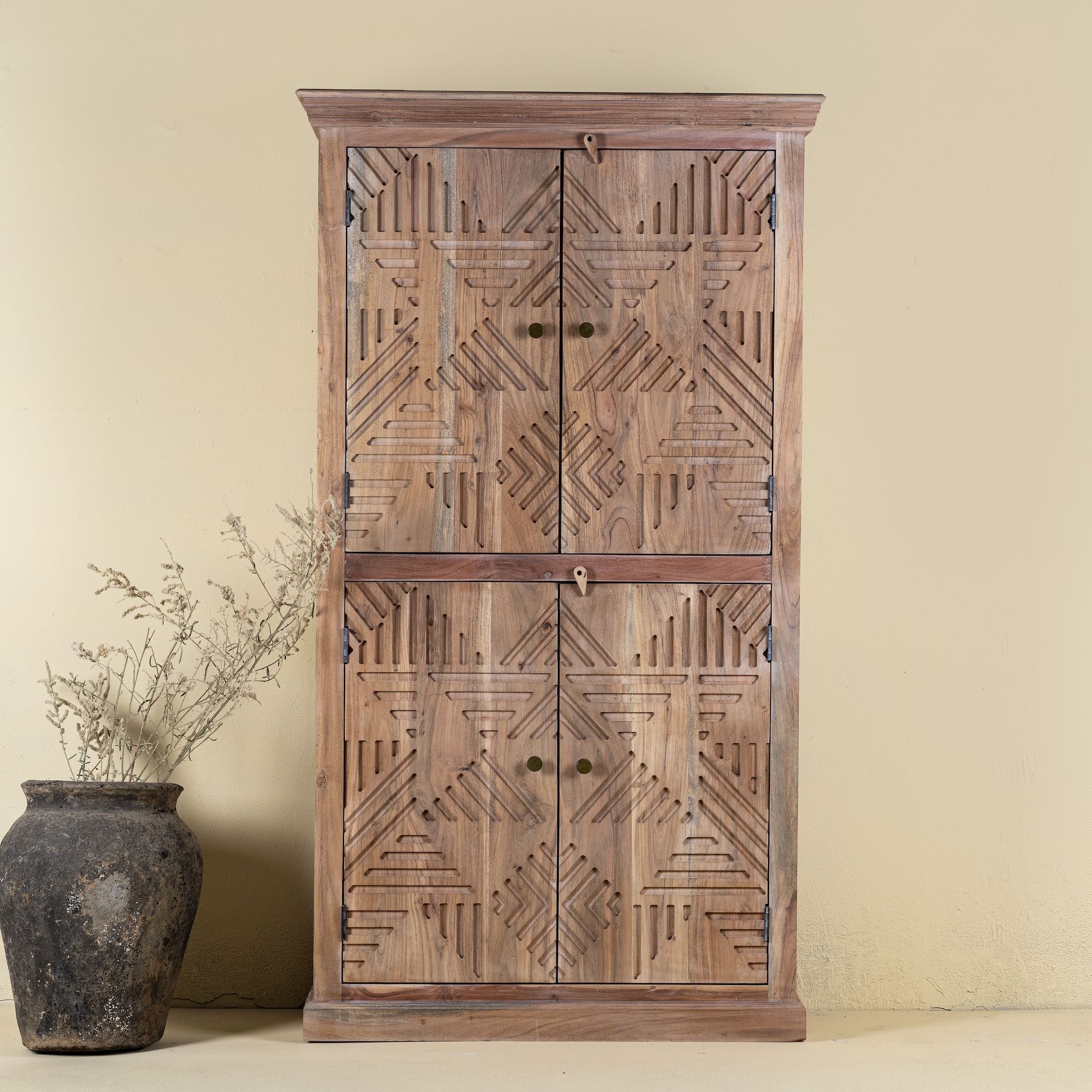 Front view of a hand crafted acacia wood cabinet with 4 doors, brass fitted door knobs and geometrical carvings.