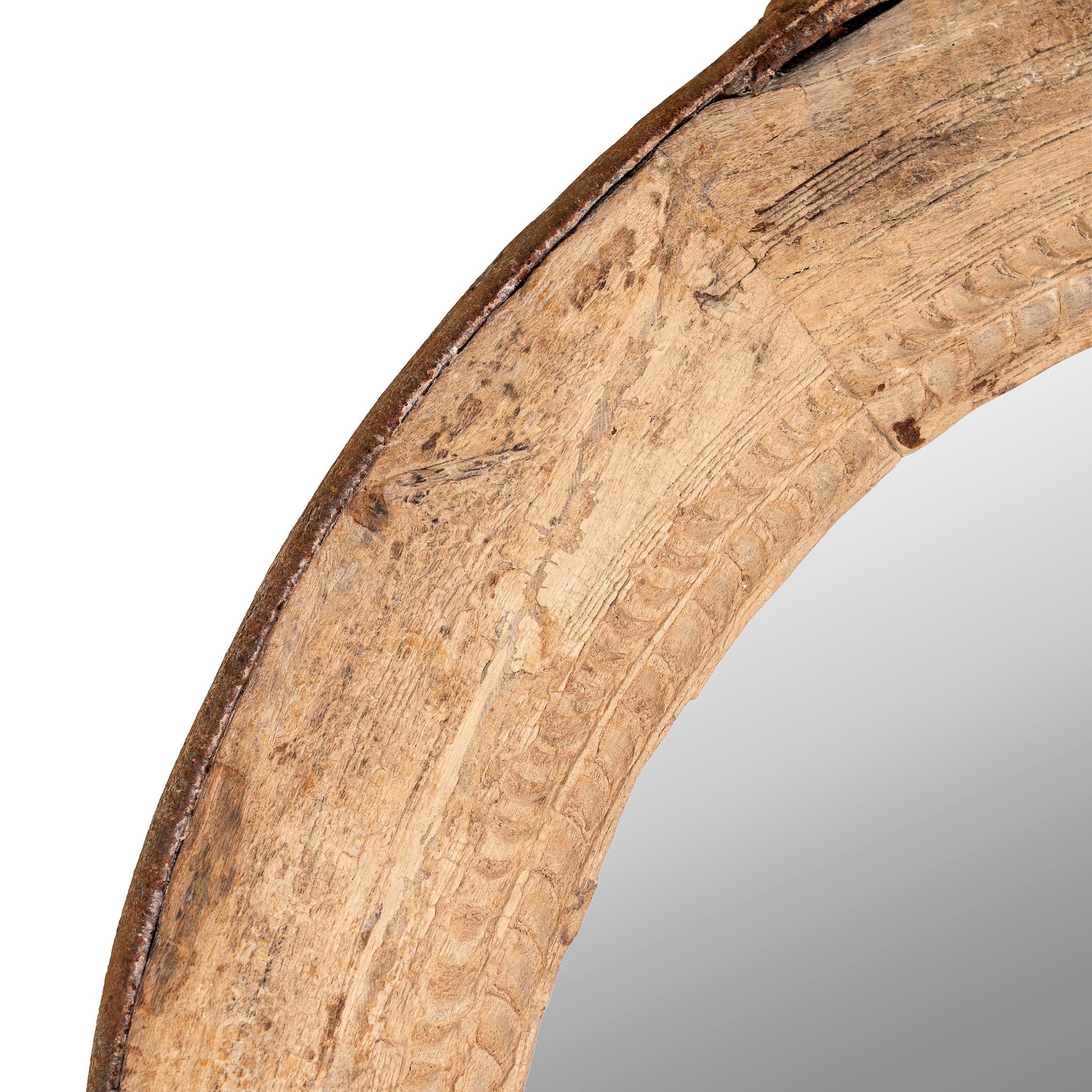 Close up image of a round carved wooden mirror with reclaimed teak frame and rustic iron edging; Indian furniture online, 110 cm diameter, 8 cm deep.