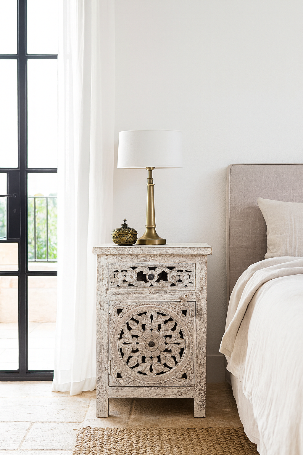 Lifestyle scene with a Whitewashed nightstand made of mango wood with Mediterranean-style carved detailing and one drawer – gagan bedside table by Om Home & Garden