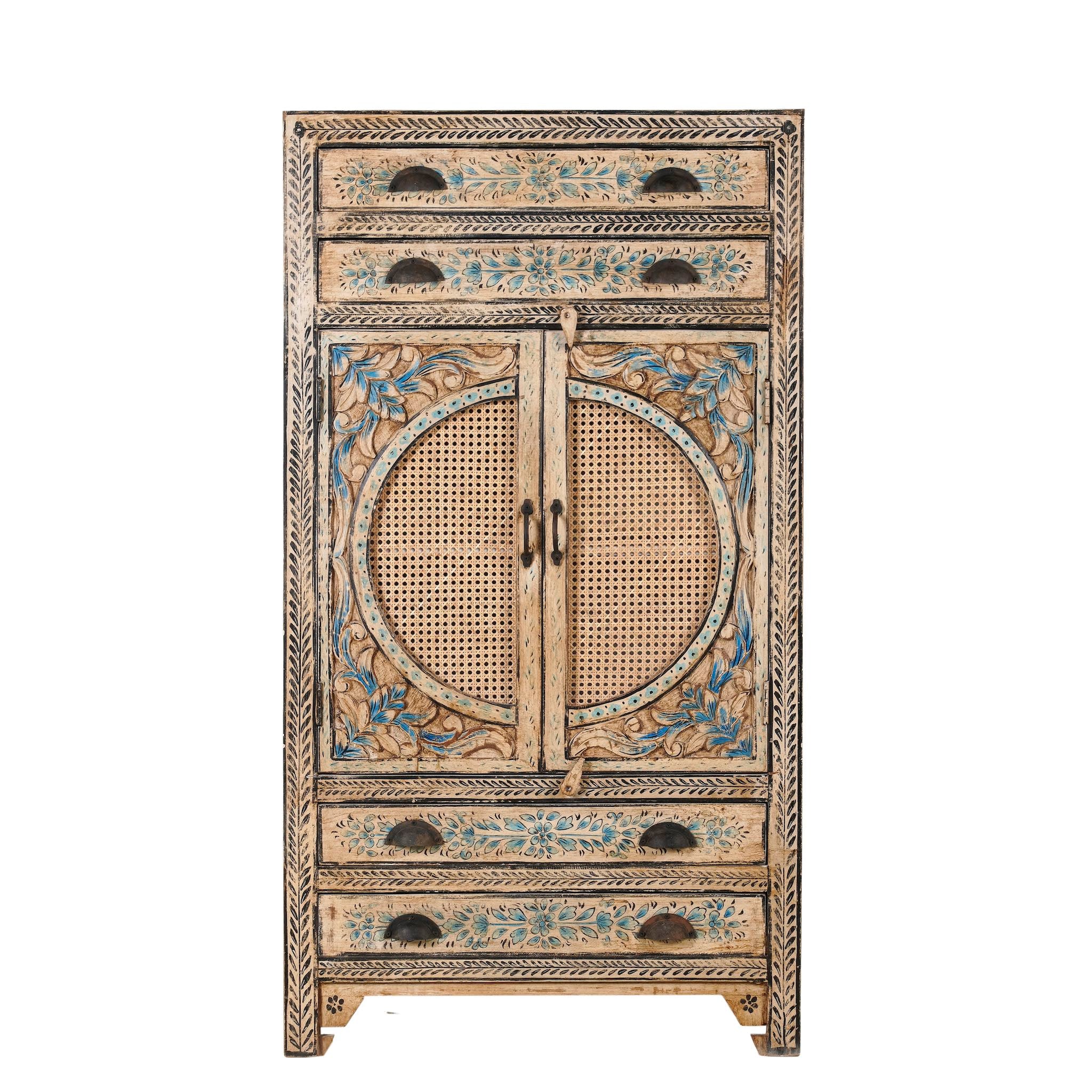 White background image of a hand-painted cabinet made from mango wood, featuring rattan inlay doors framed by a carved circular motif, floral blue and green accents, and five drawers for additional storage.