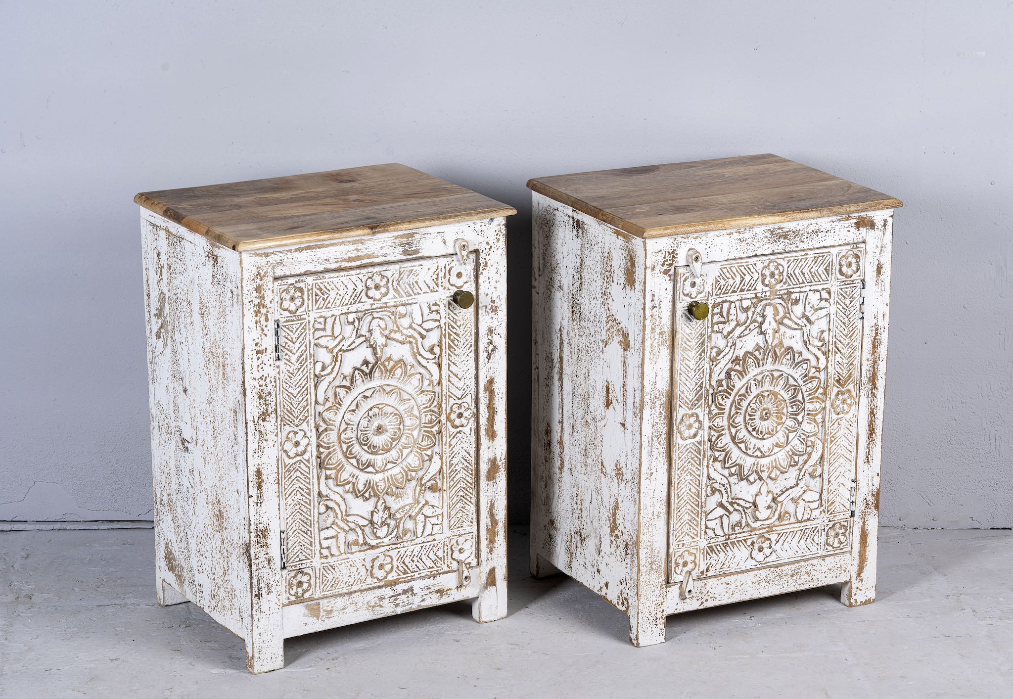 Side angle image with open door of a pair of whitewashed reclaimed wood nightstands with intricately carved mandala and floral patterns, handcrafted in rustic vintage style.