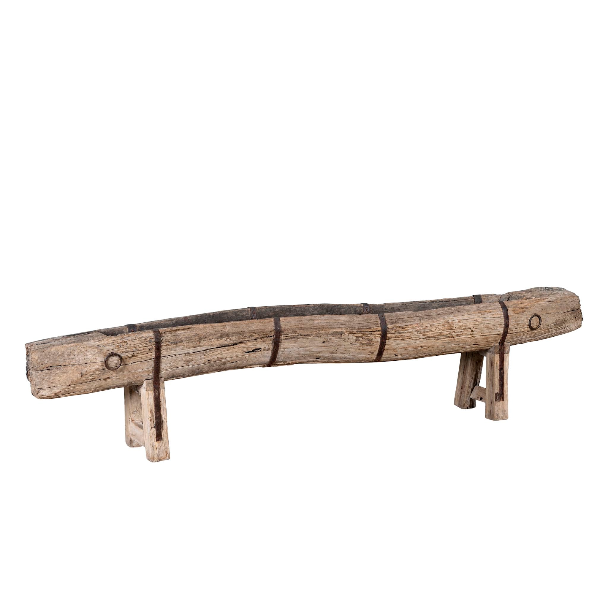 White background image of an antique console table repurposed from reclaimed teak wood feeding trough with carved details and iron fittings; unique furniture ideal for rustic interiors, compatible with teak wood benches, 234 × 31 × 61 cm.