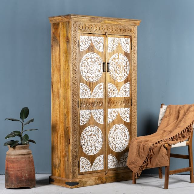 Side angle image of a carved wood furniture wardrobe made from mango wood with whitewashed floral doors, wooden wardrobe in Ibiza-inspired style, 100 × 40 × 180 cm.