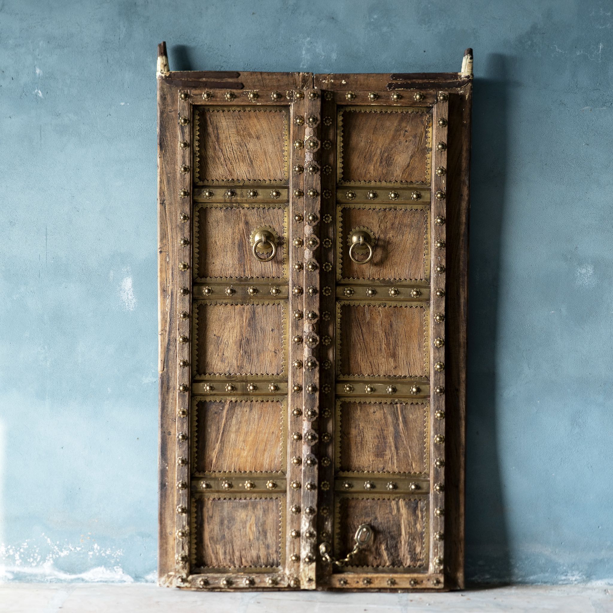 Antique Indian temple door made of old teak with original brass fittings, locks, and ring handles, featuring a richly aged patina from a historic Jain temple.