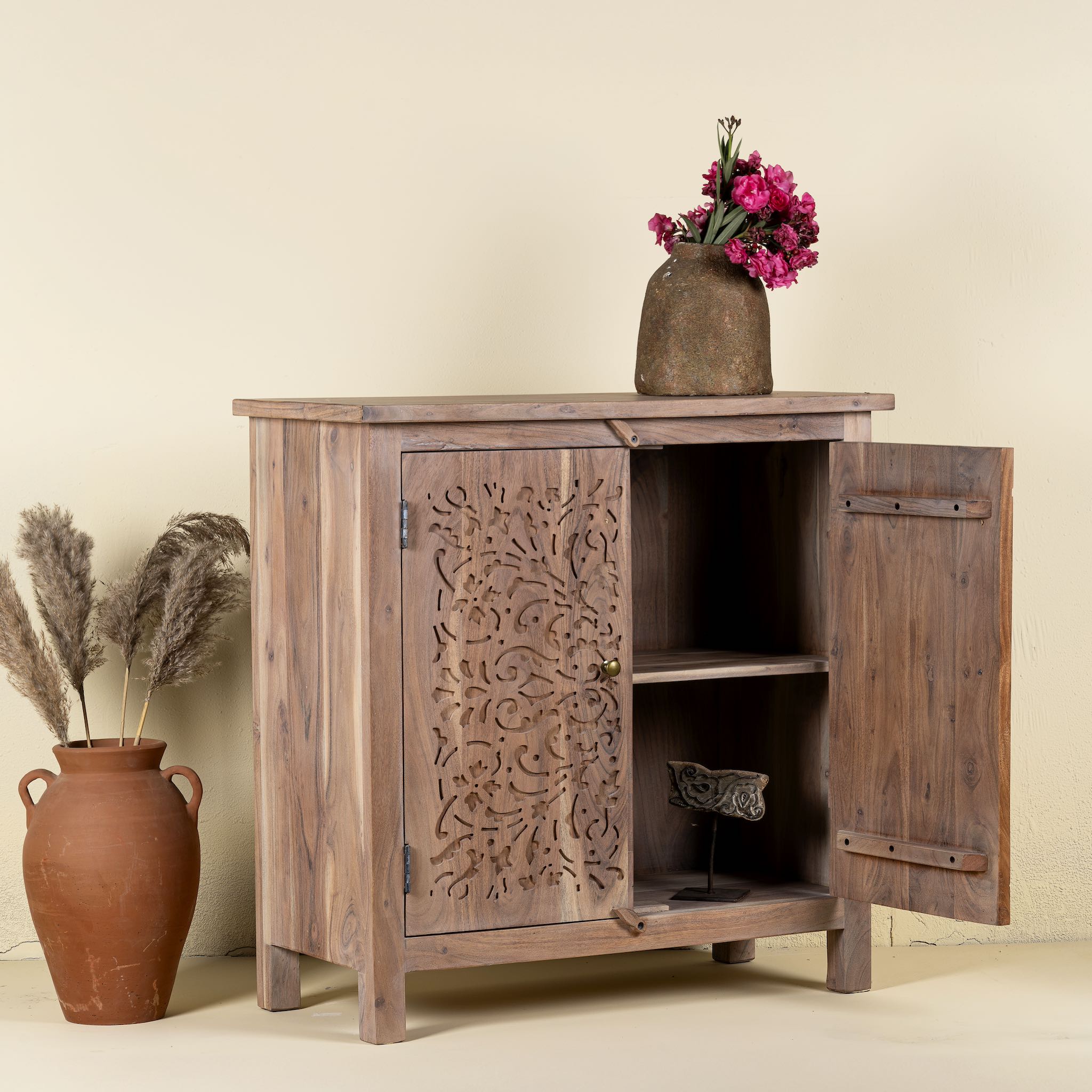 Open Door image of a carved acacia wood cupboard with floral cutout doors and brass knobs, 90 × 40 × 90 cm.