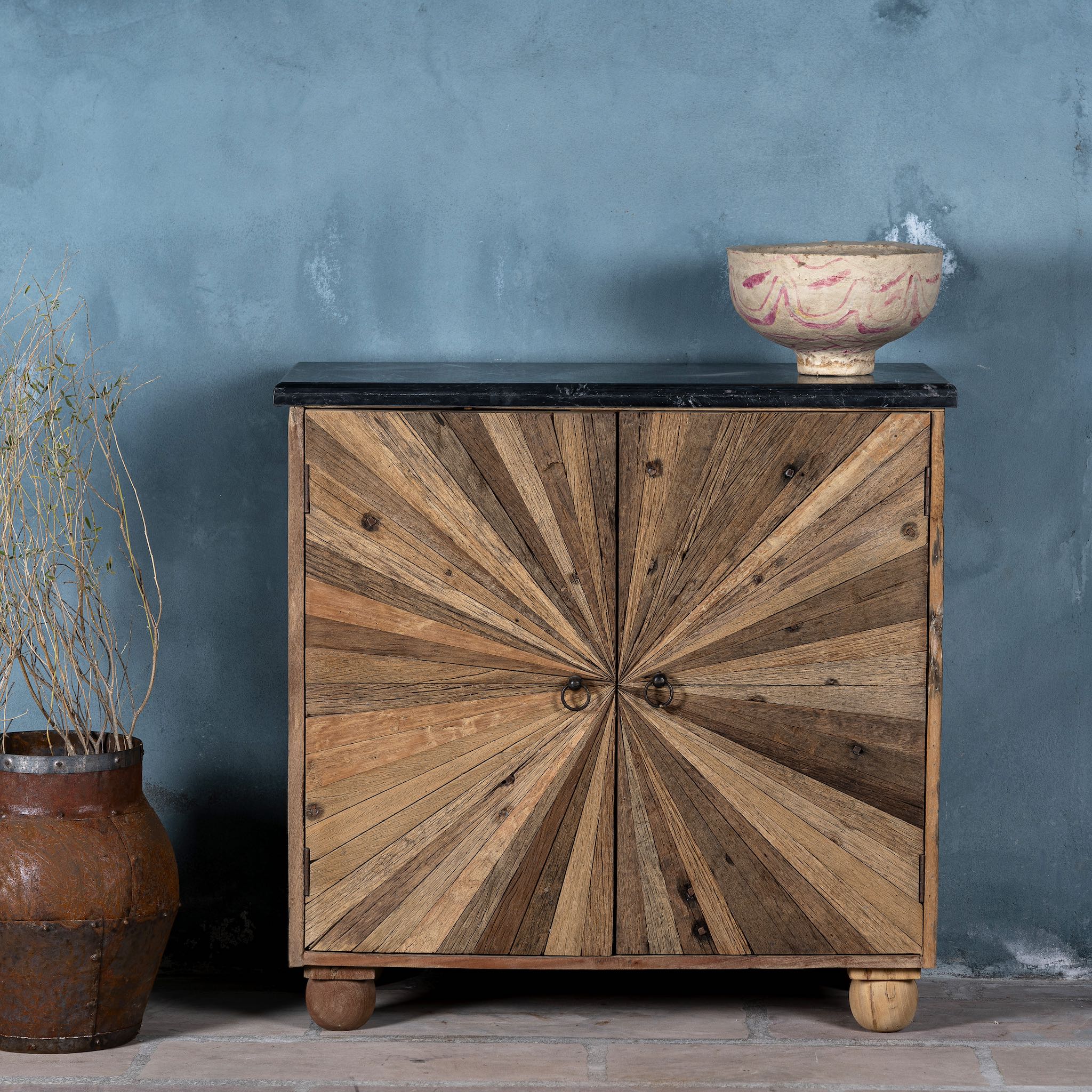 Reclaimed wood sideboard with sunburst carved doors, sliding black marble top, and rustic finish, ideal for rustic interior design.