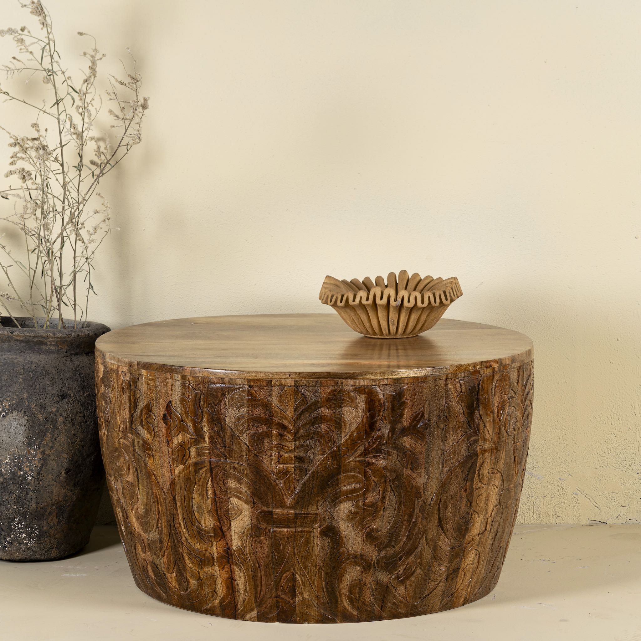 Front view of a elegant round hand carved coffee table made of sustainable Mango wood with floral design.