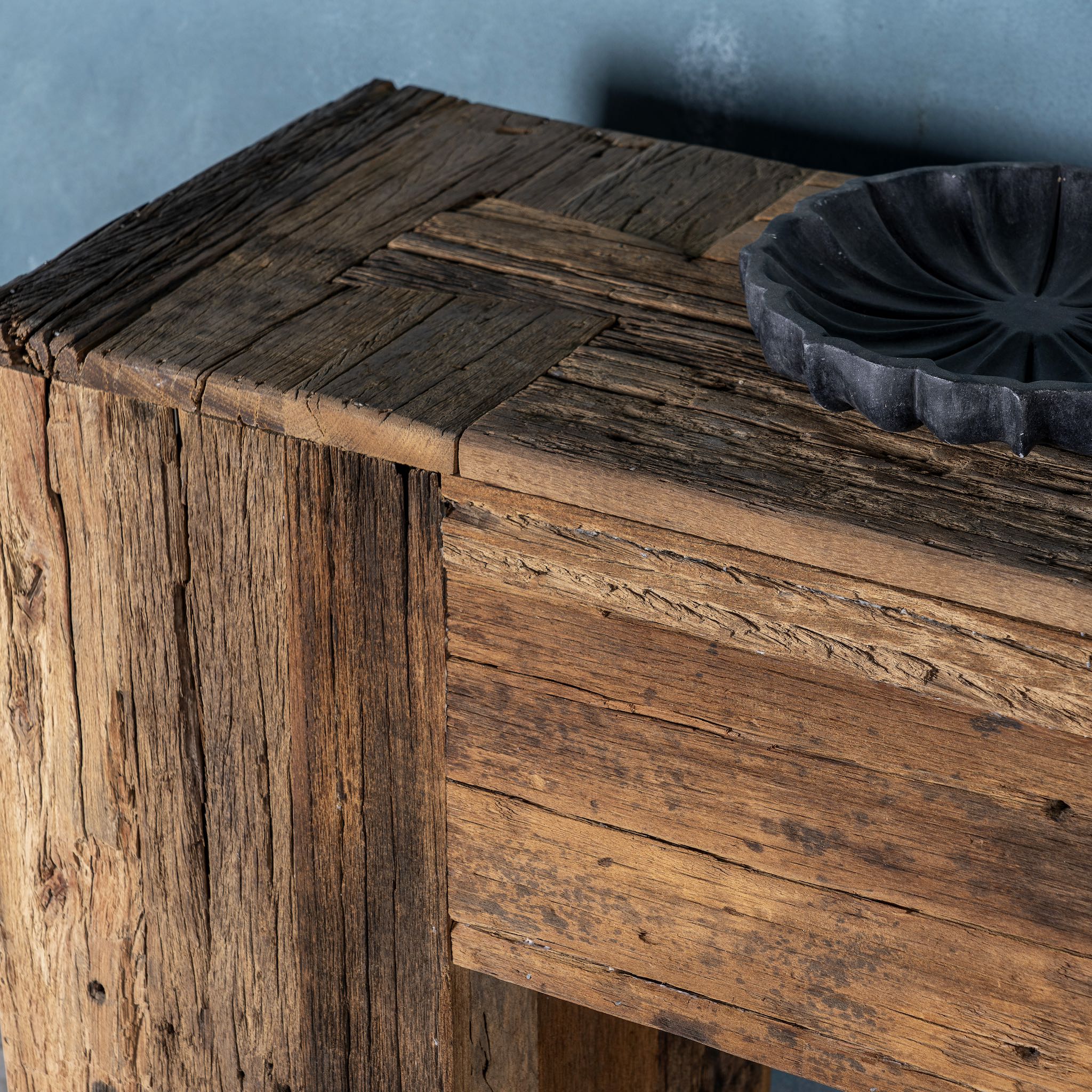 Close up image of a rustic minimalistic console table made from reclaimed wood with preserved imperfections, block legs, 250 × 40 × 90 cm.