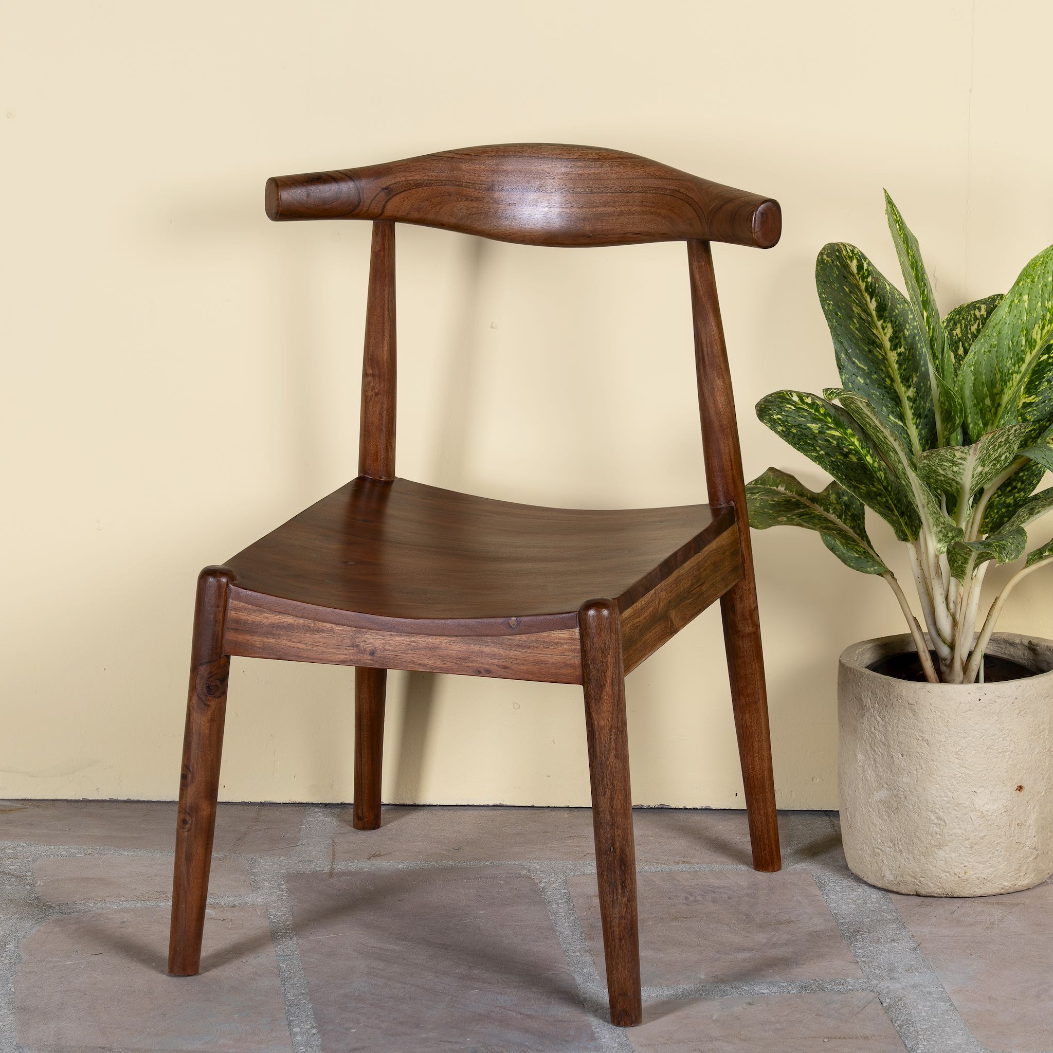 Side angle image of an acacia wood chair with sculptural backrest, minimalist wooden armchair for dining or living rooms, 50 × 50 × 90 cm.