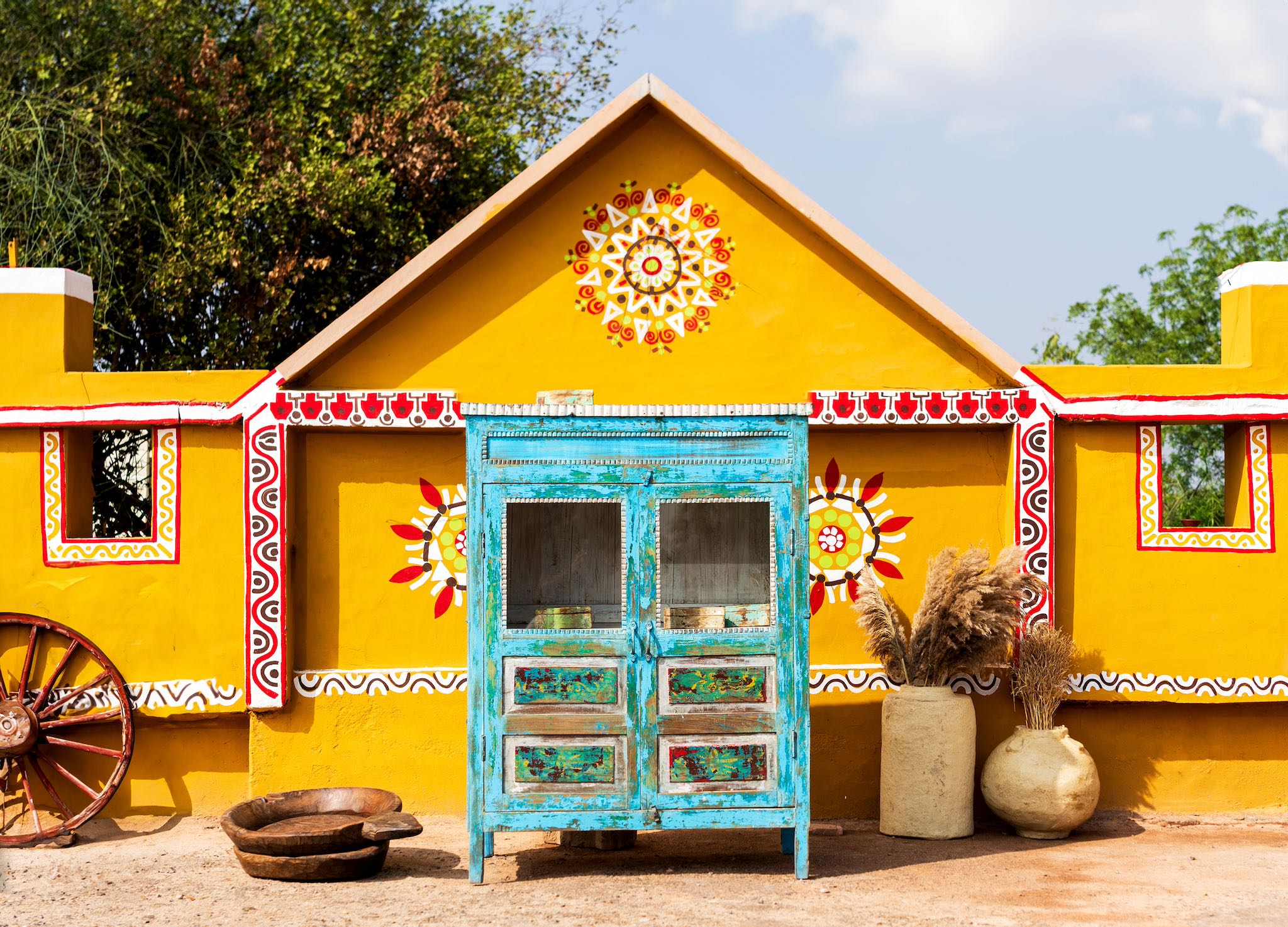 Indian Village scene view of a blue vintage glass door cabinet made of reclaimed wood with added decoration.