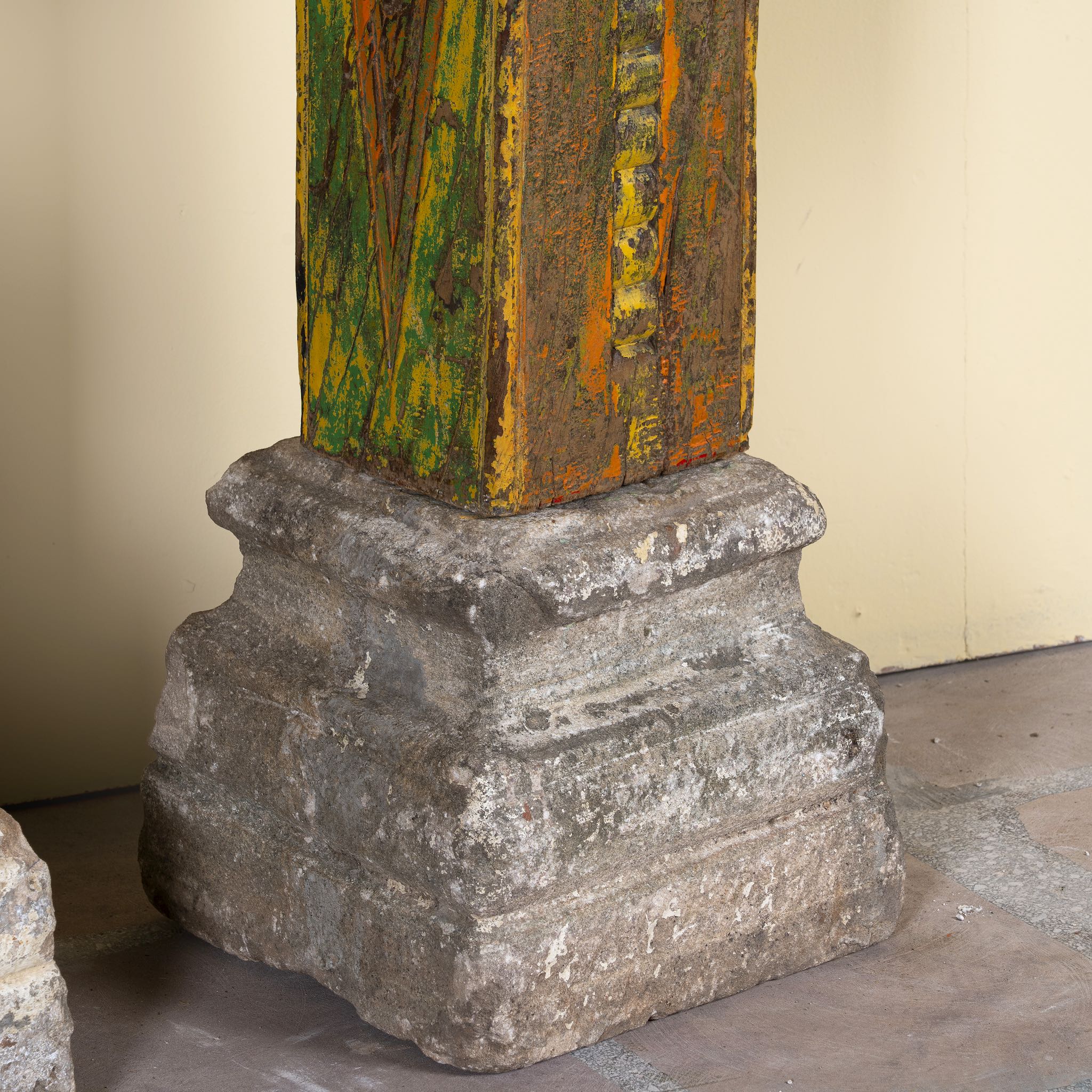 Close up of the stone base of an antique pair of carved wooden house pillars with original stone bases, weathered multicolour finish, 210 cm high, vintage home decor and boho chic living room accents.