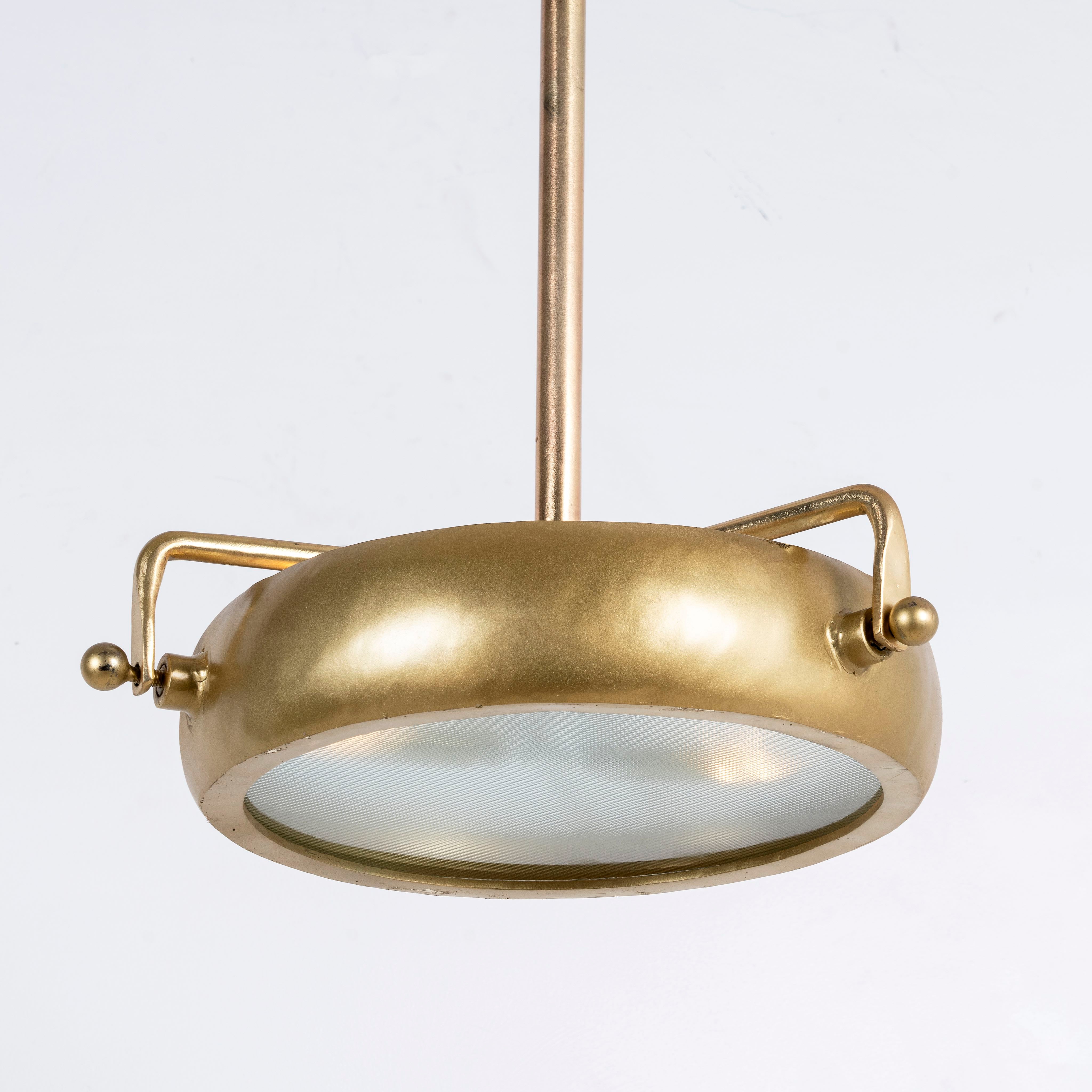 Side angle image of a round artsy pendant lamp with clear hand-blown glass and brass-plated iron frame – retro lighting piece ideal for kitchens, dining rooms, or living areas.