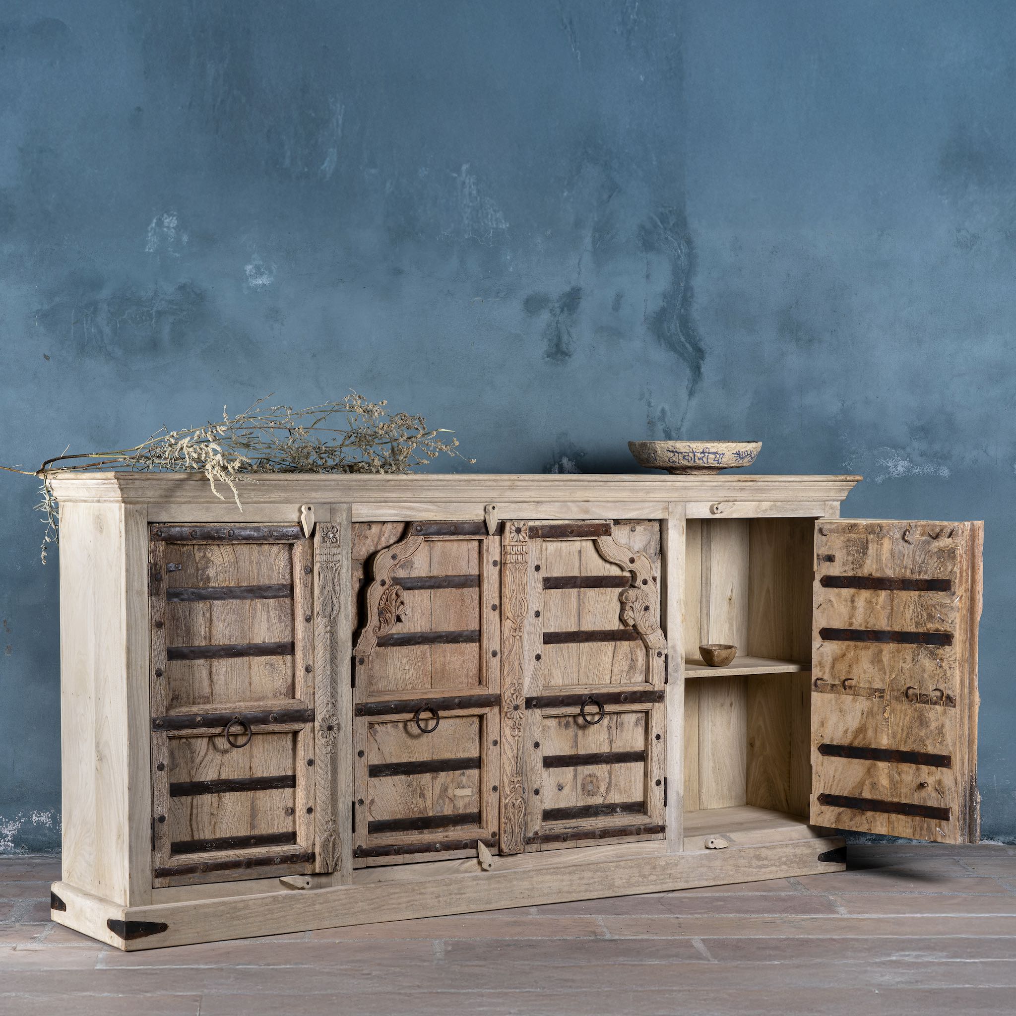 Open door view of a reclaimed teak furniture sideboard with antique Indian doors, old door cabinet with hand-carved details and iron accents, 220 × 45 × 110 cm.