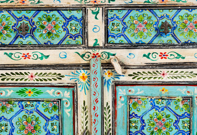Close up image of a vintage hand painted furniture cupboard in reclaimed wood with floral and geometric motifs, off-white distressed finish, 90 × 40 × 90 cm.
