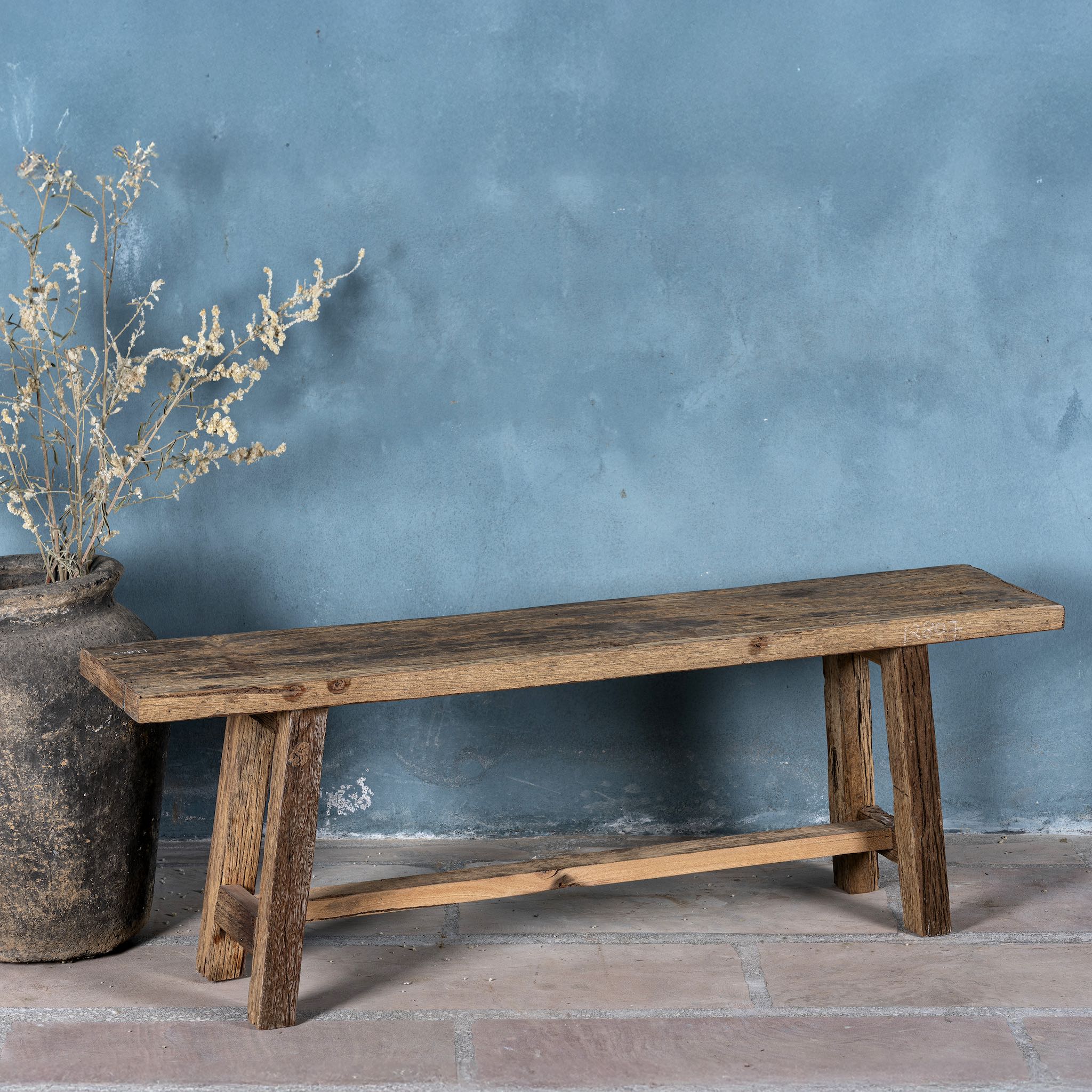 Front view image of a rustic driftwood bench made from reclaimed wood with aged finish and angled legs; handcrafted rustic wood furniture, 130 × 25 × 45 cm.