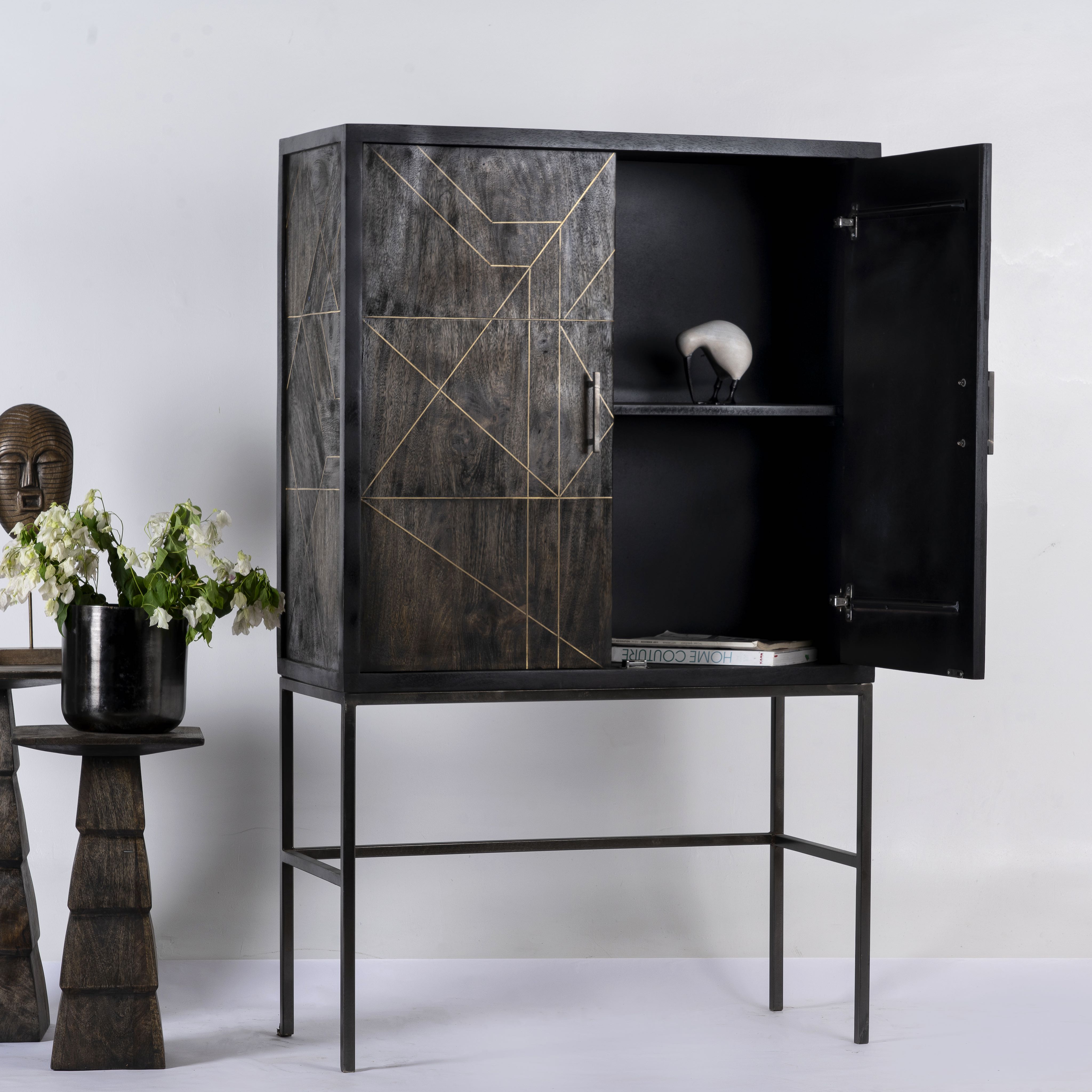 Side angle image with open door of a black wooden cabinet with handcrafted copper inlays and nickel-plated metal base—an artisanal furniture piece with a refined minimalistic style.