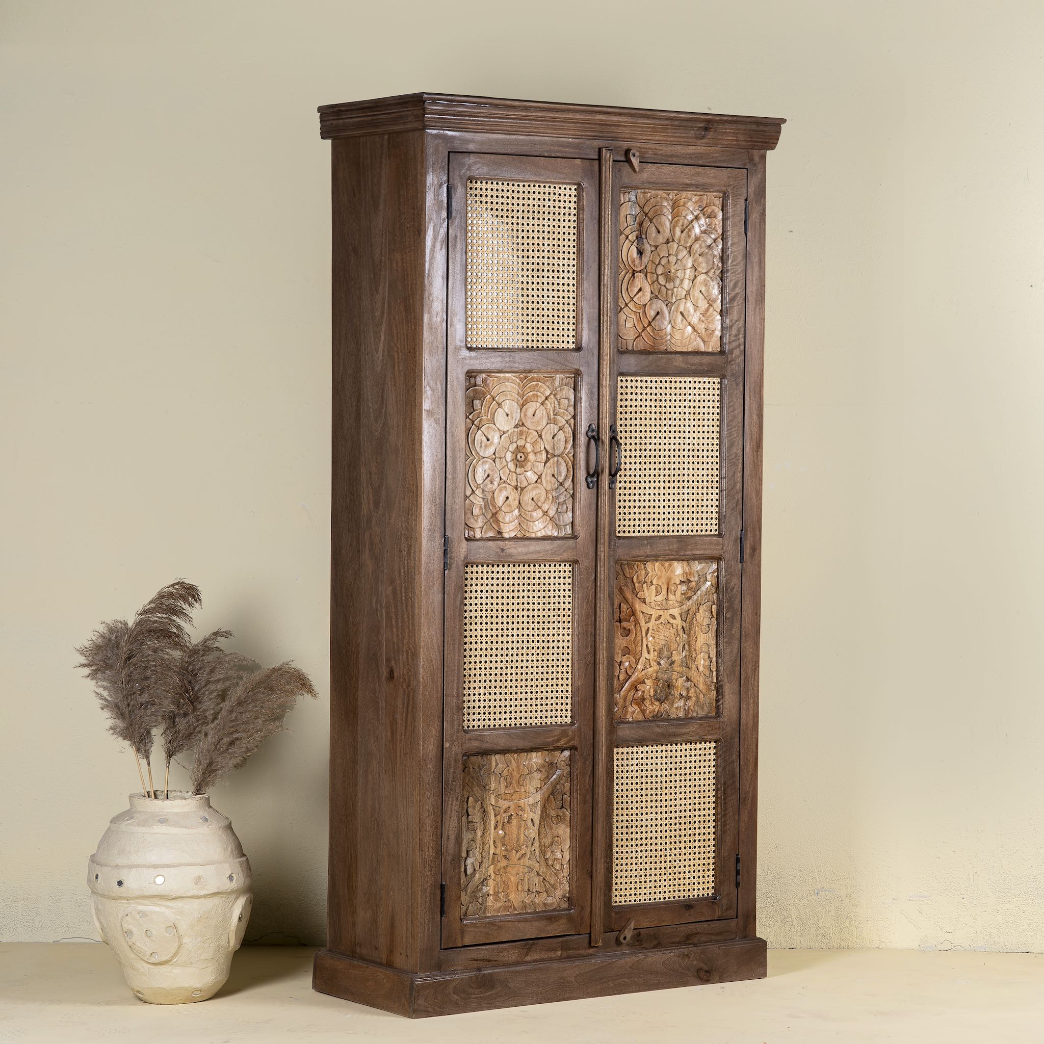 Side angle image of a tall mango wood furniture cabinet with hand-carved details and woven rattan doors, artisan rattan furniture, 90 × 40 × 180 cm.