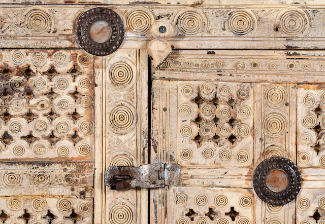 Close up image of a sandblasted antique Indian teak chest with hand-carved details, original iron fittings, and a naturally aged finish, ideal for bohemian or vintage-inspired interiors.