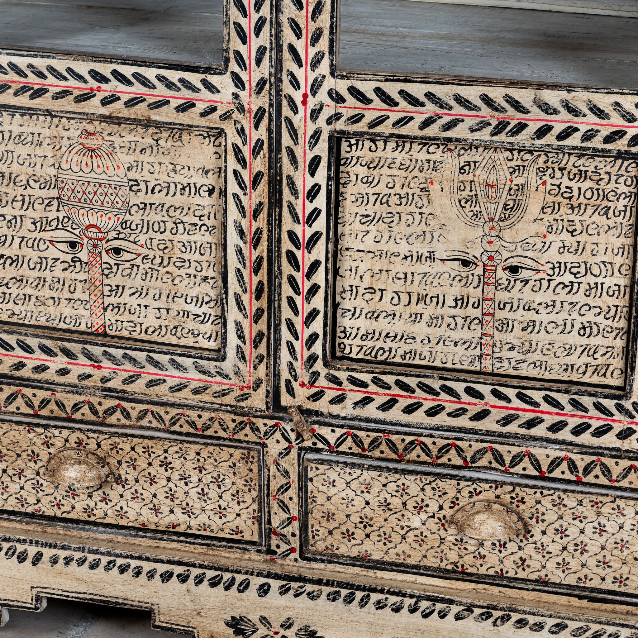 Close up image of a of a hand-painted display cabinet made from recycled wood with glass doors – sustainable furniture featuring Sanskrit motifs and traditional Indian craftsmanship.
