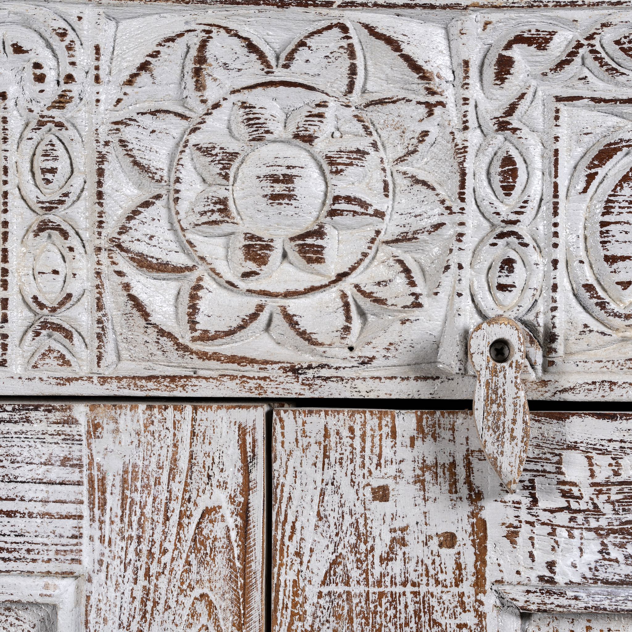 Close up image of a grey-washed reclaimed wood cabinet with hand-carved floral and sunburst detailing, a vintage furniture piece perfect for rustic or bohemian interiors.